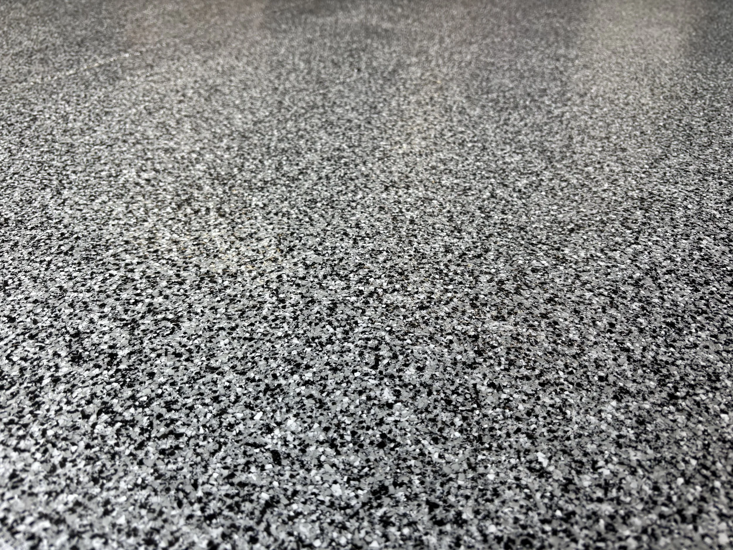 Close-up of a textured, speckled gray surface, possibly asphalt or granite.