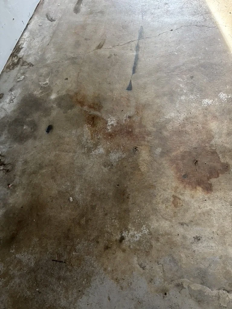 Dirty concrete floor with stains, cracks, and scattered debris.