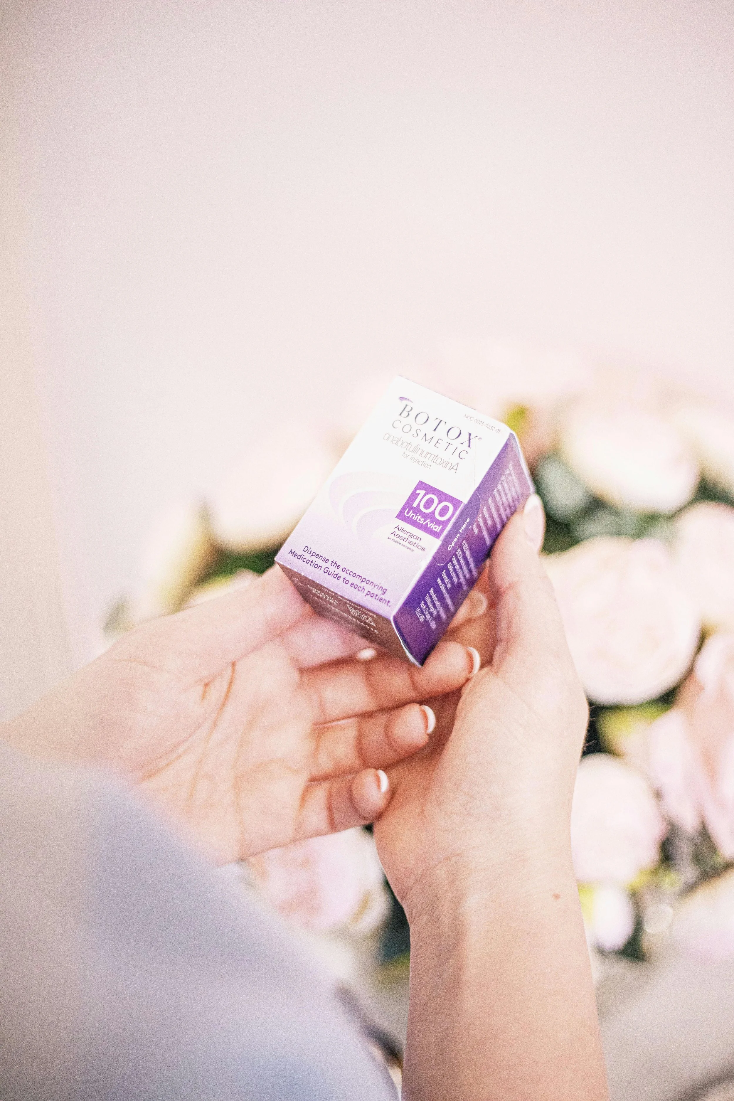 Well-manicured hands holding a box of Botox Cosmetic vials.