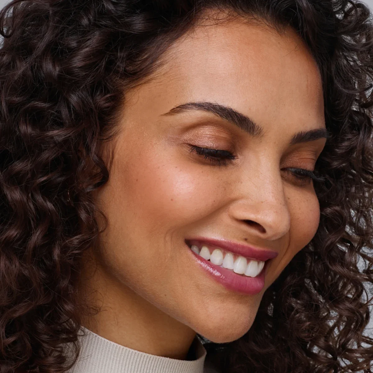 Smiling woman looking down and to the right, featured in Alle Rewards loyalty program.