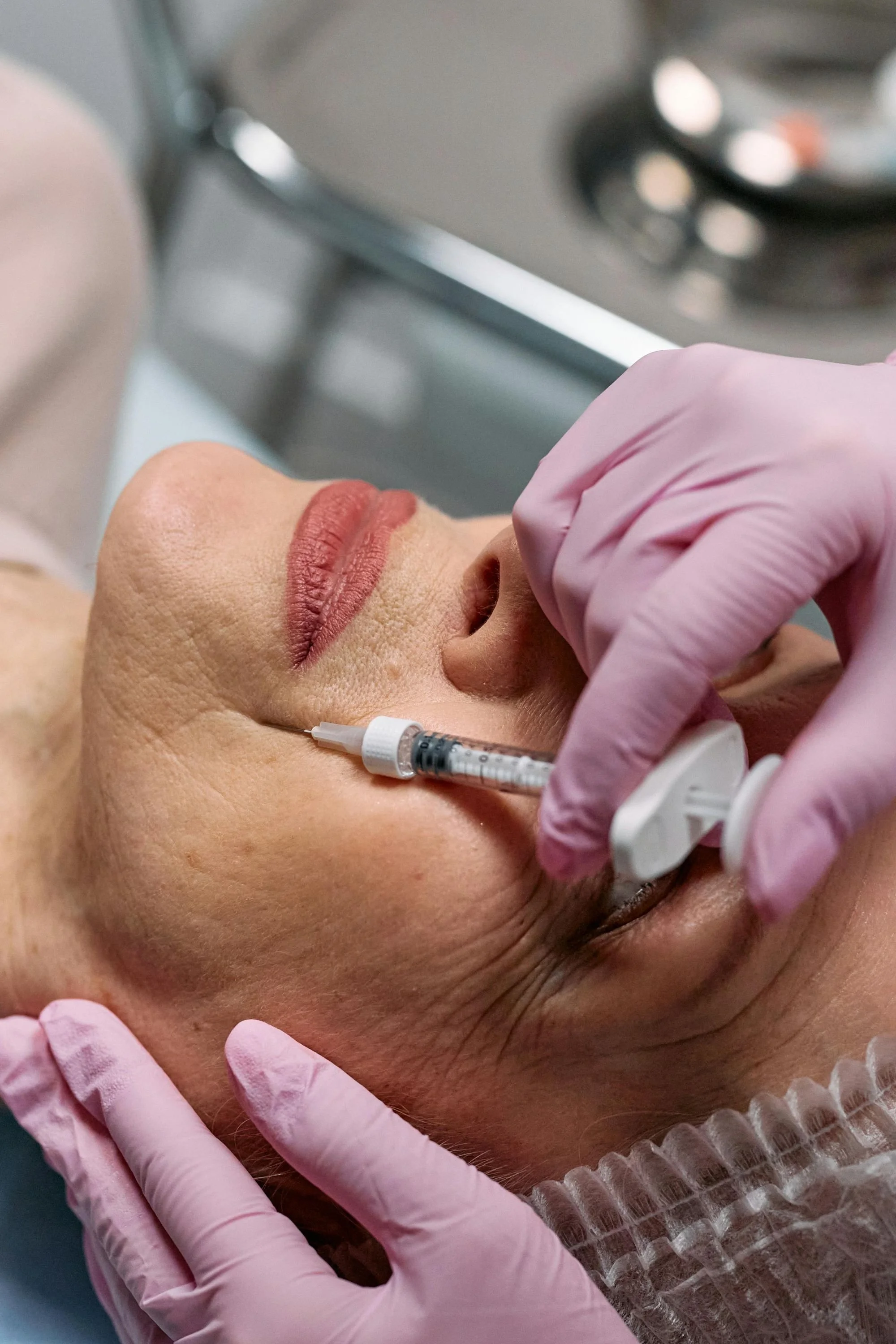 A close up of a biostimulator being injected into an older woman's jowl area.