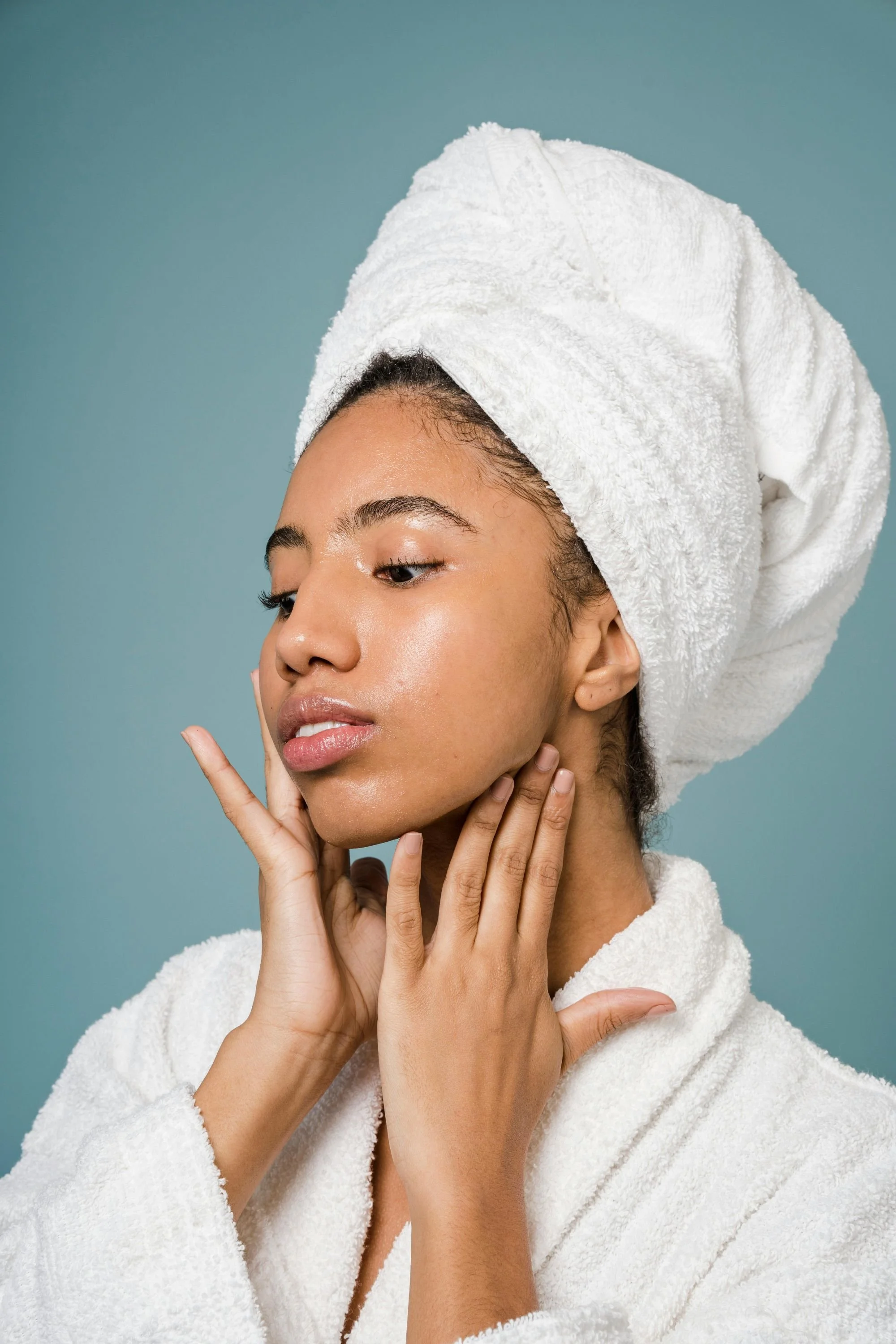 Close-up of a woman with radiant, hydrated skin touching her face.