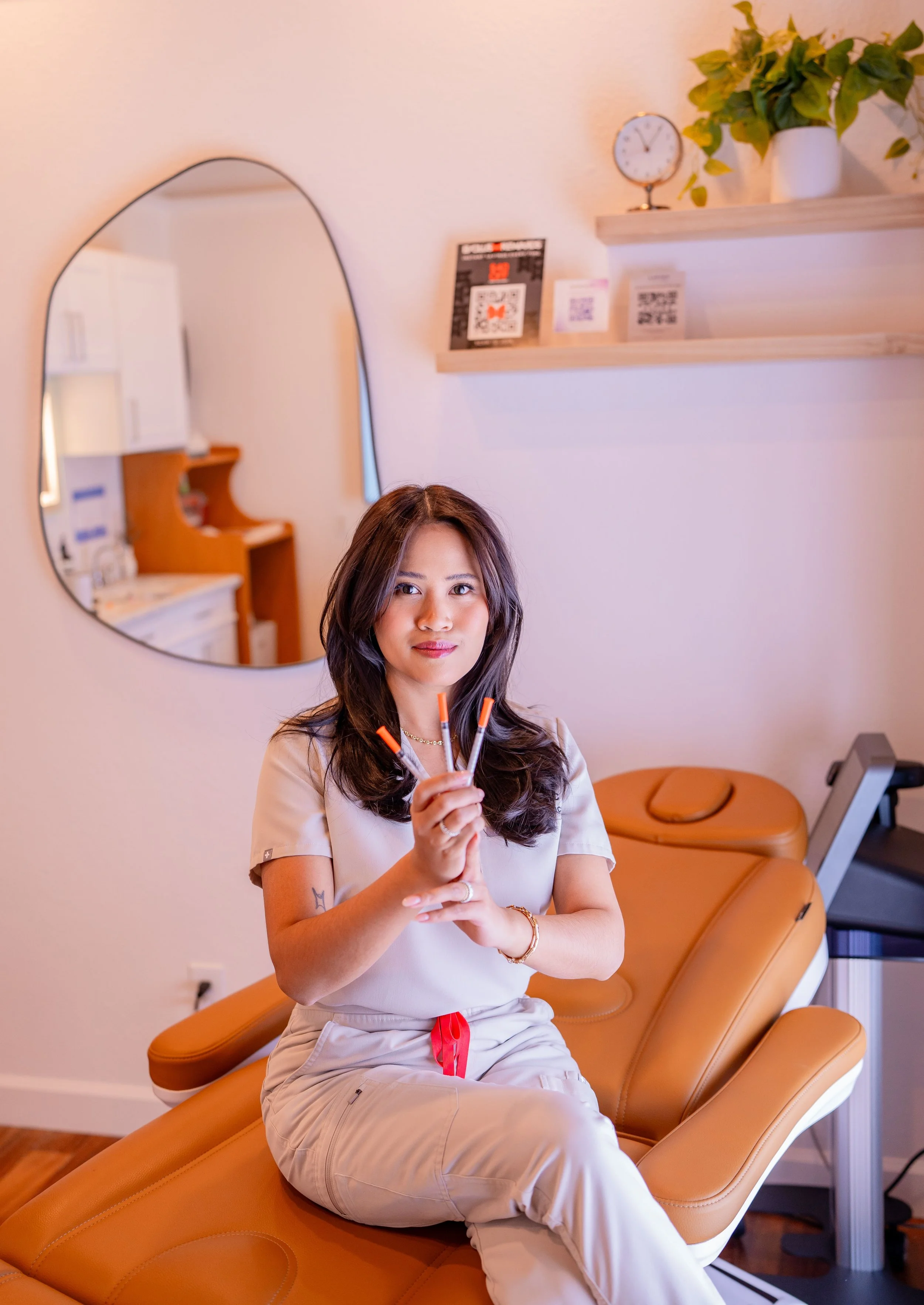 Gail Torres, board-certified nurse practitioner, holding three aesthetic injection syringes inside her med spa.