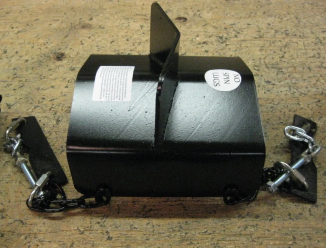 A black metal box with a warning sticker and a card, attached to chains on each side, placed on a wooden surface.