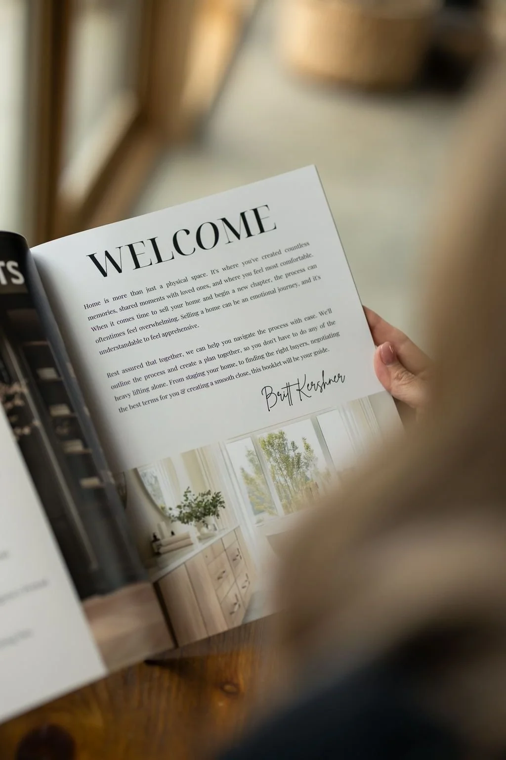 Trusted Utah real estate agent, Britt Kershner, looking at the 'welcome' page of a Kershner & Co. buyer guide booklet.