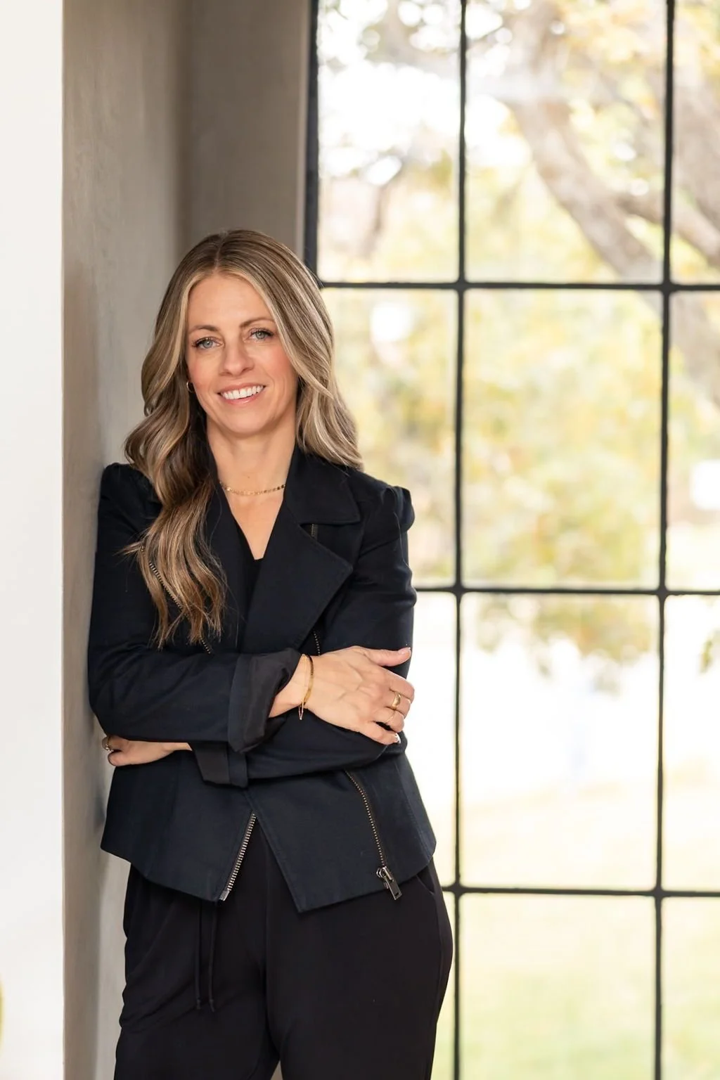 Britt Kershner, realtor and owner of Kershner & Co., dressed in a black pantsuit smiling at the camera while leaning against a wall.