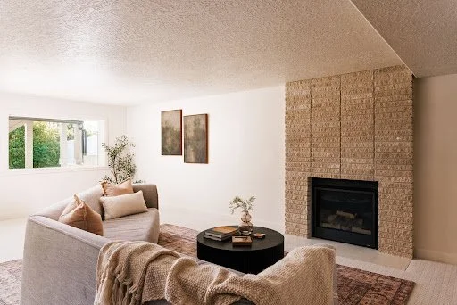 Bright, inviting living room with a brick fireplace, neutral furnishings, and natural light, showcasing a welcoming space prepared for a Utah home sale this fall.