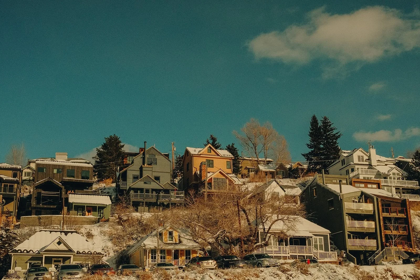 Colorful houses nestled on a snowy Utah hillside under a clear blue sky in winter.