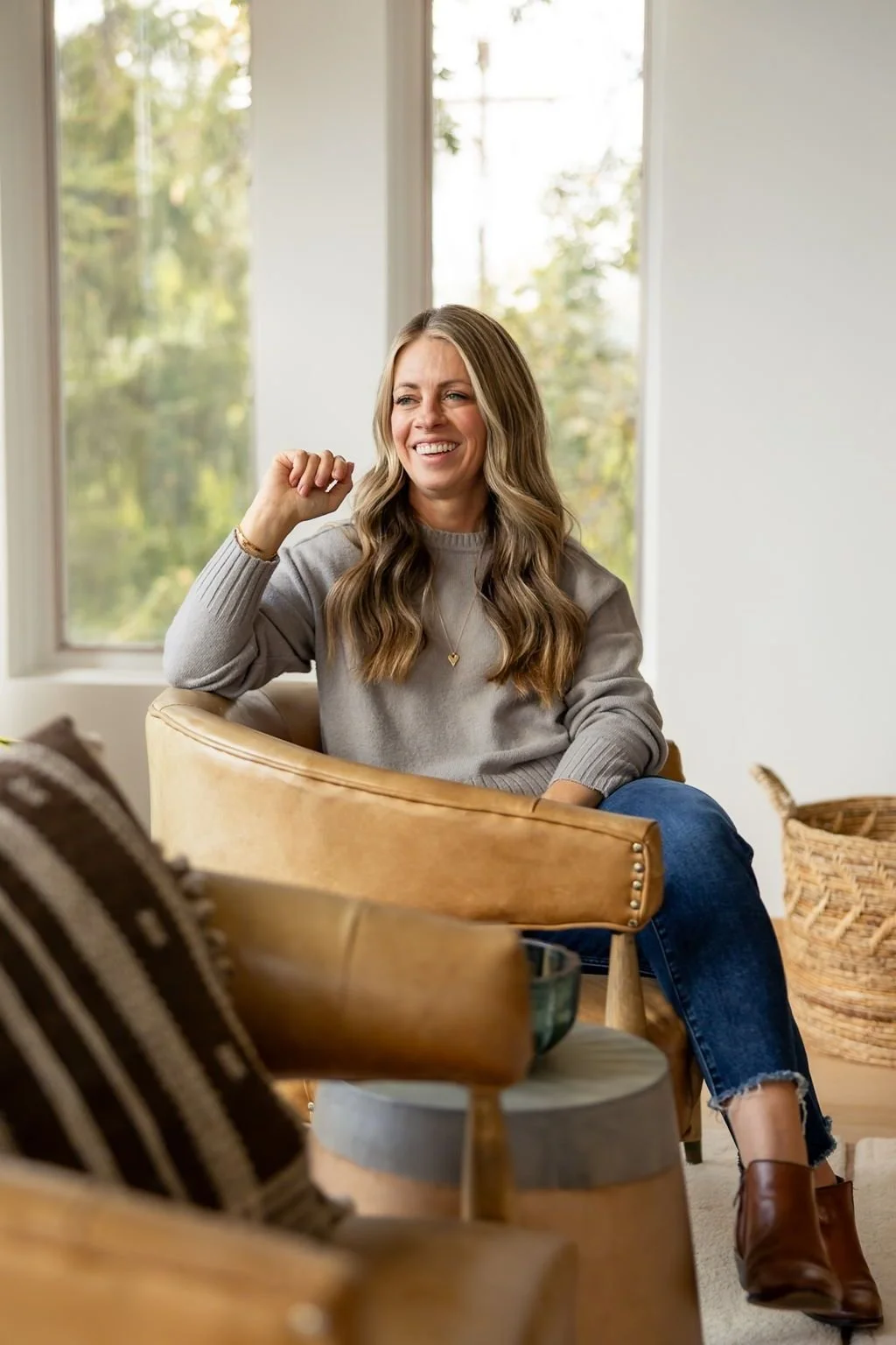 Britt Kershner, Utah realtor, sitting in a tan leather armchair in a southwestern style living room.