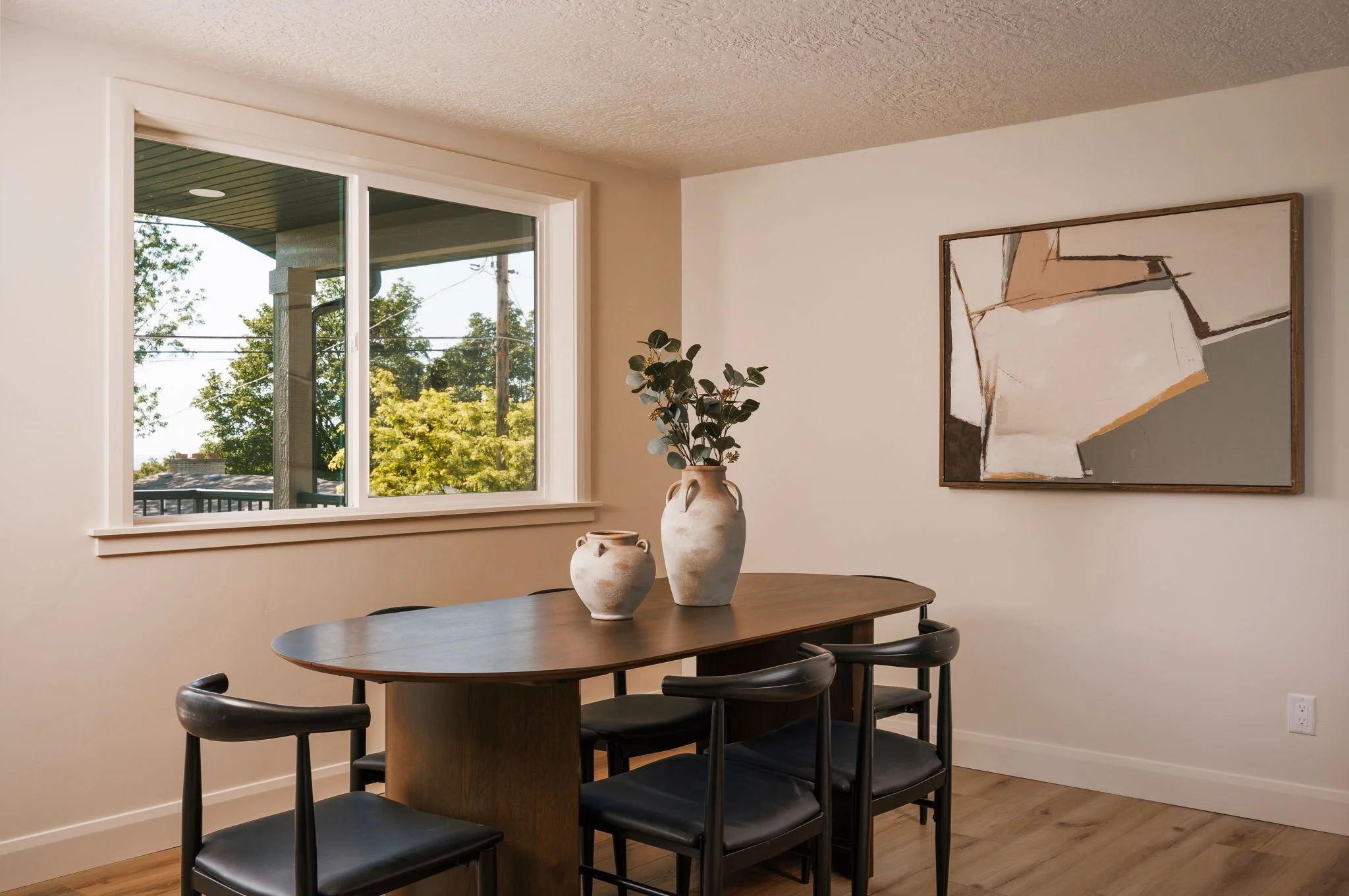 Modern dining area with a dark wood table, black chairs, and large windows overlooking greenery, illustrating the lifestyle and home interiors of Salt Lake City's East Bench neighborhood.