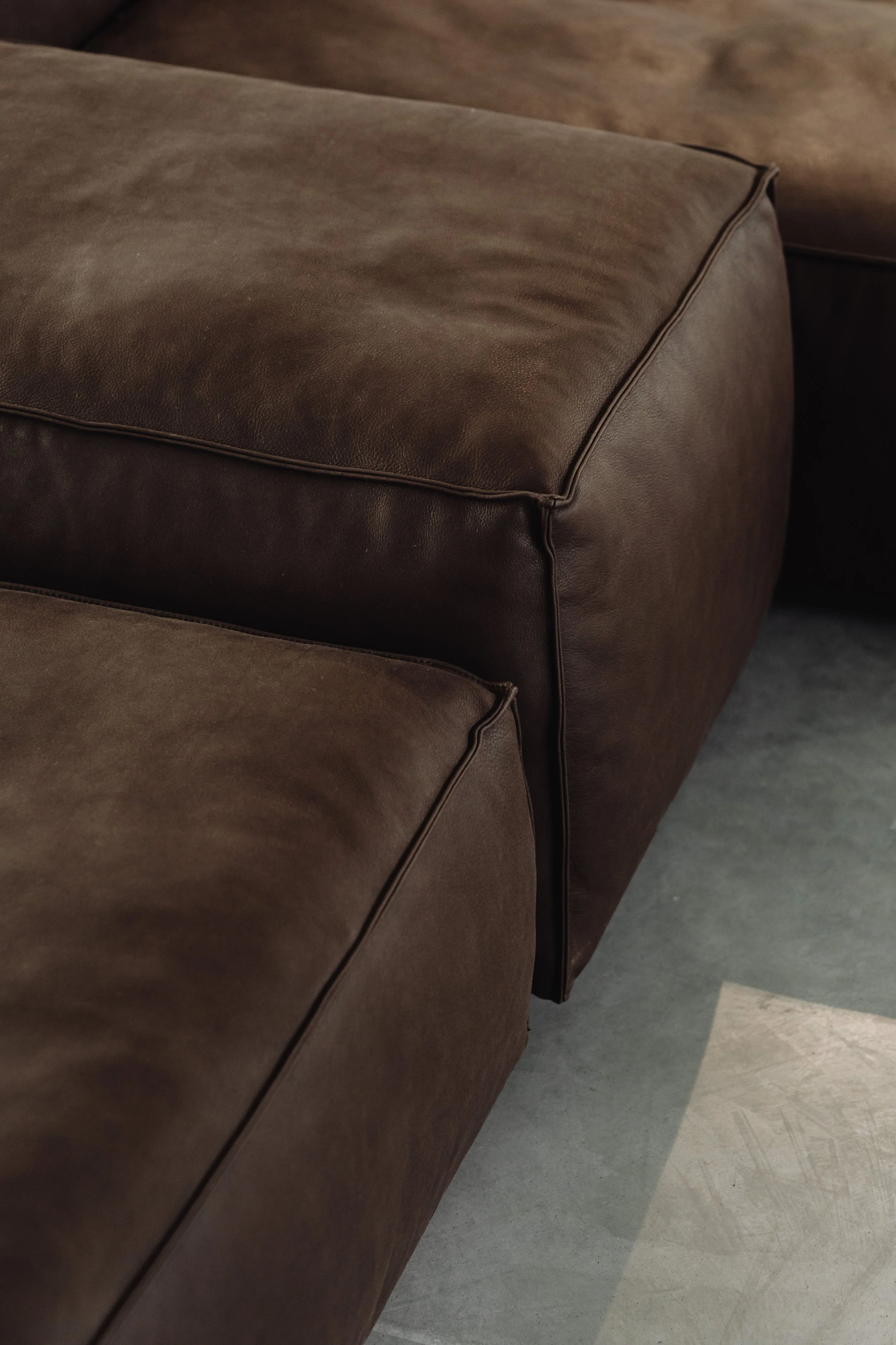 A close up of a premium dark brown brushed leather couch, focusing on the texture of the fabric.