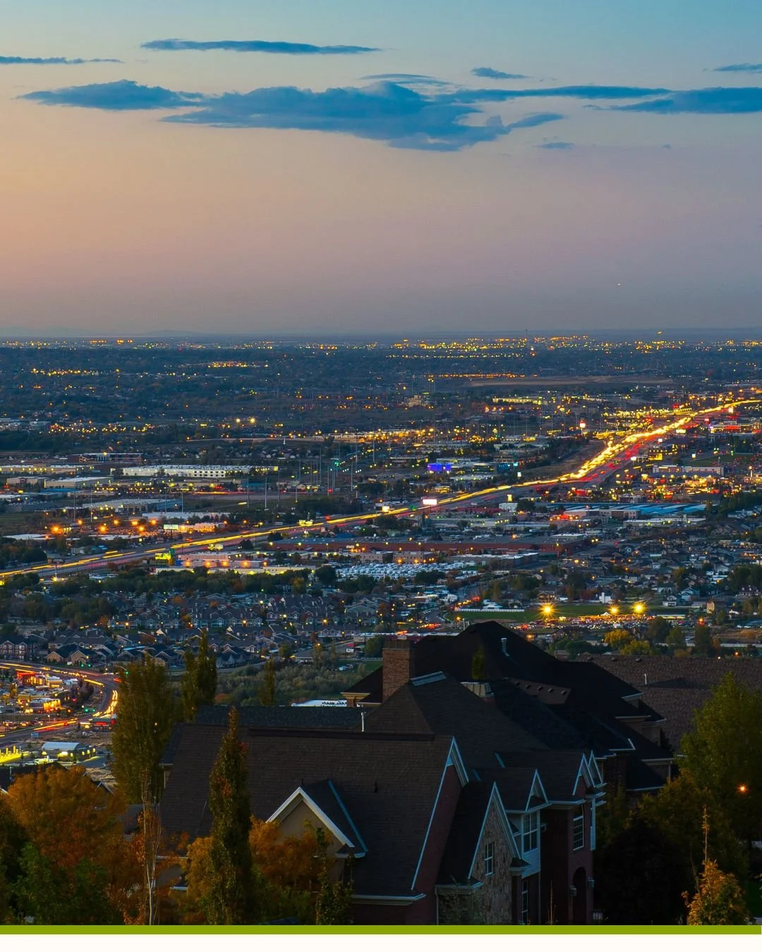 A wide shot of the city of Draper, Utah during dusk, the car headlights in traffic glowing as the city starts getting dark.
