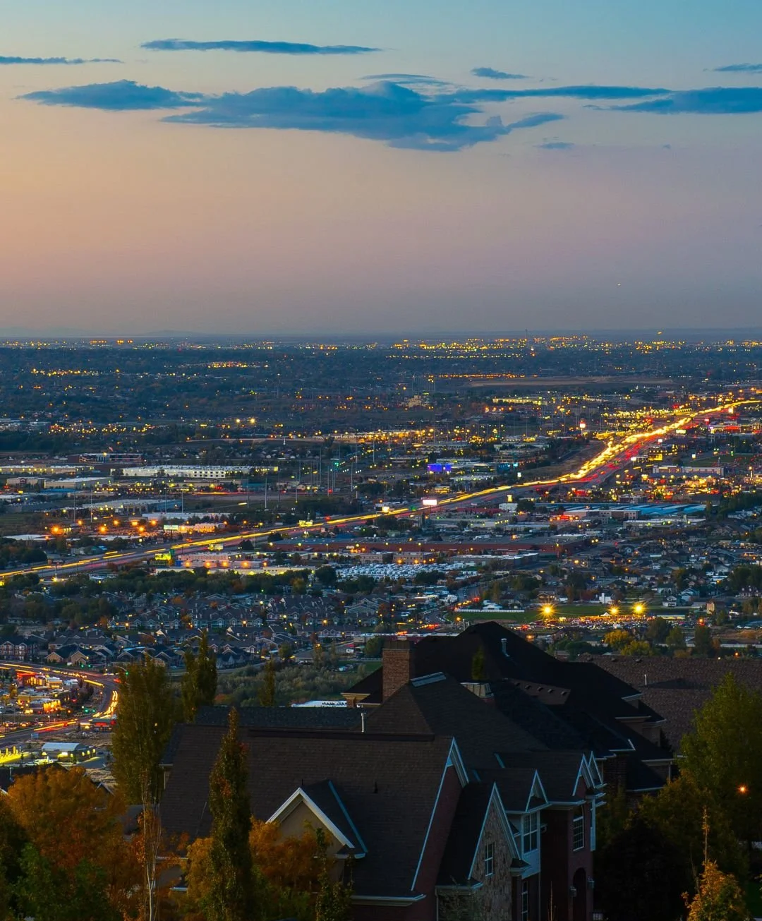 A wide shot of the city of Draper, Utah during dusk, the car headlights in traffic glowing as the city starts getting dark.png