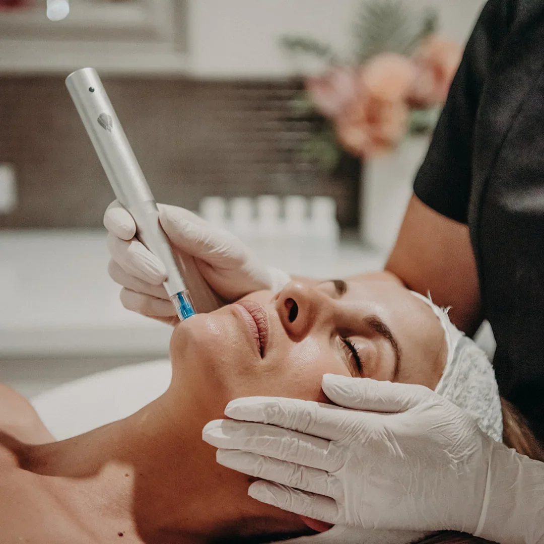 A woman receiving a facial treatment with a device applied to her face, in a spa or clinic setting.