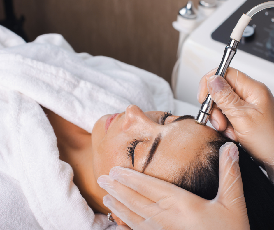 Person receiving a facial treatment with a handheld device in a spa or clinic setting.