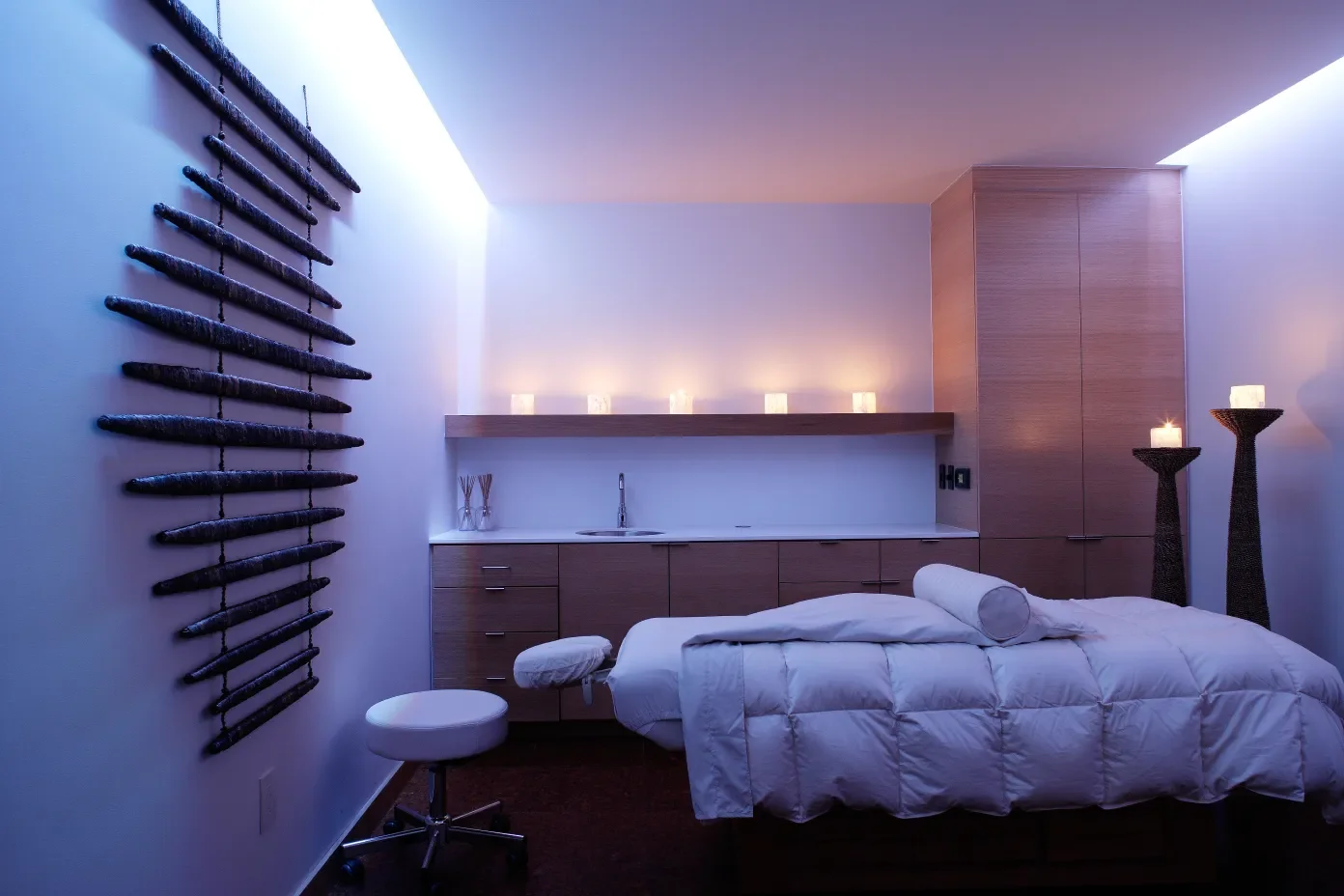 A modern, minimalist bedroom with a bed, candles, and artistic decor, featuring soft, ambient lighting.