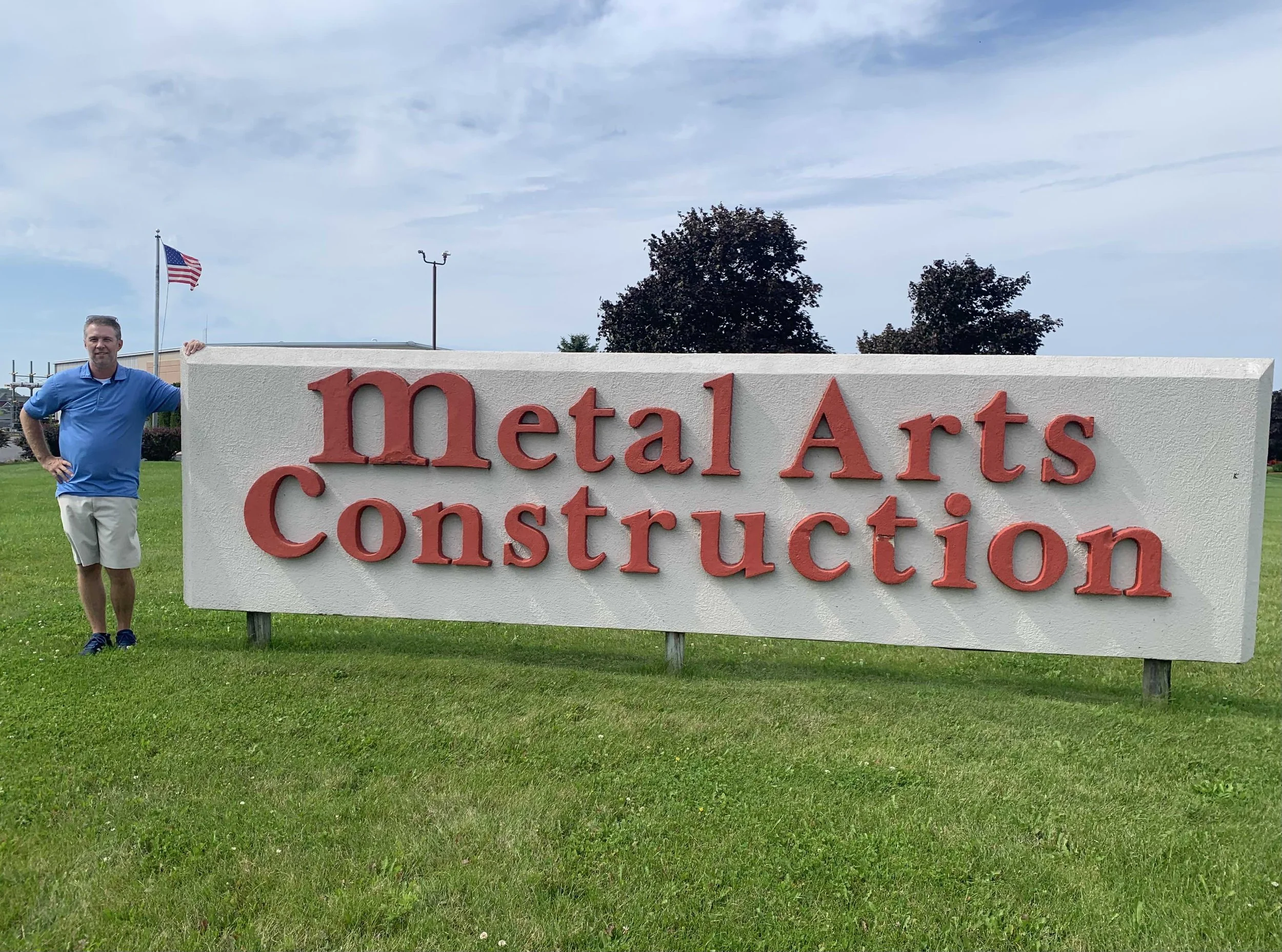 Man standing outside in front of a Metal Arts Construction sign