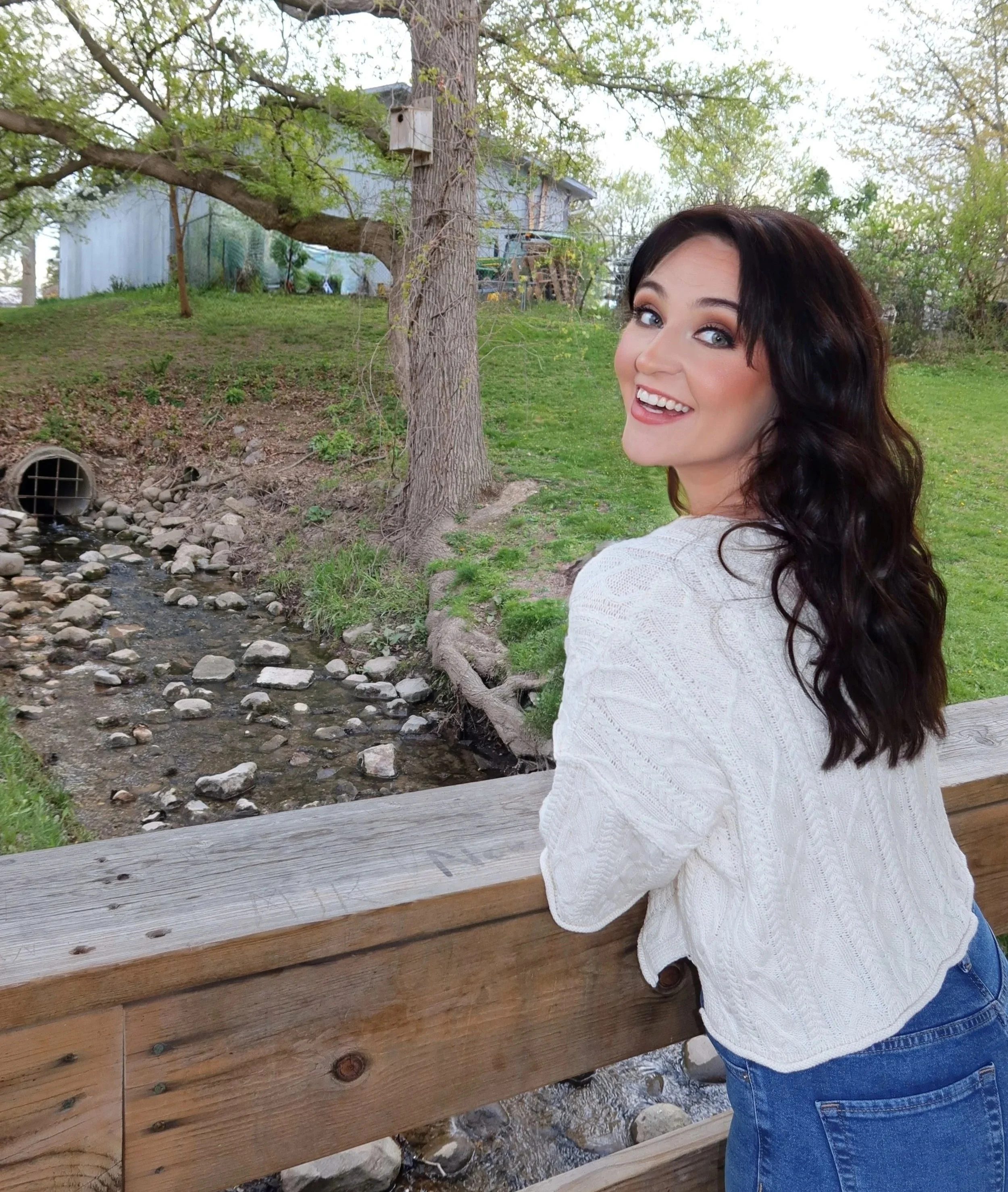 A women looking backwards smiling on a bridge.