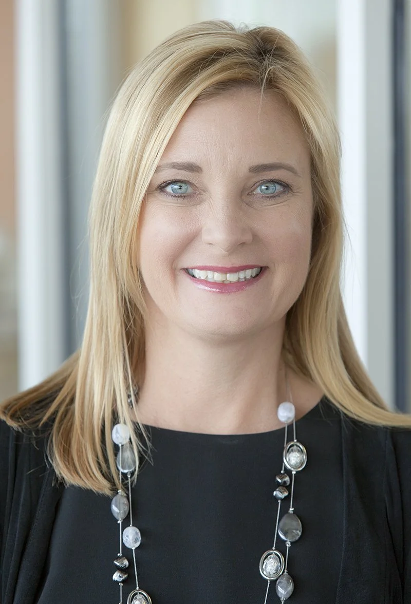 A professional headshot of a blonde woman smiling