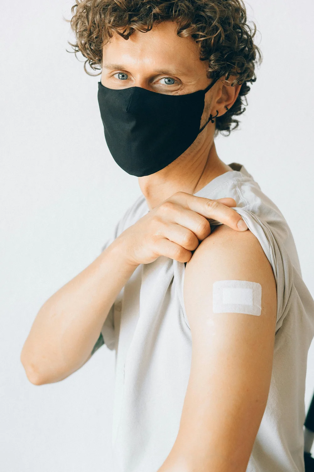 Stock model wearing a mask and showing a bandage on an upper arm