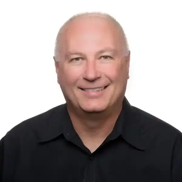 A smiling middle-aged man with a shaved head, wearing a black shirt, against a plain white background.