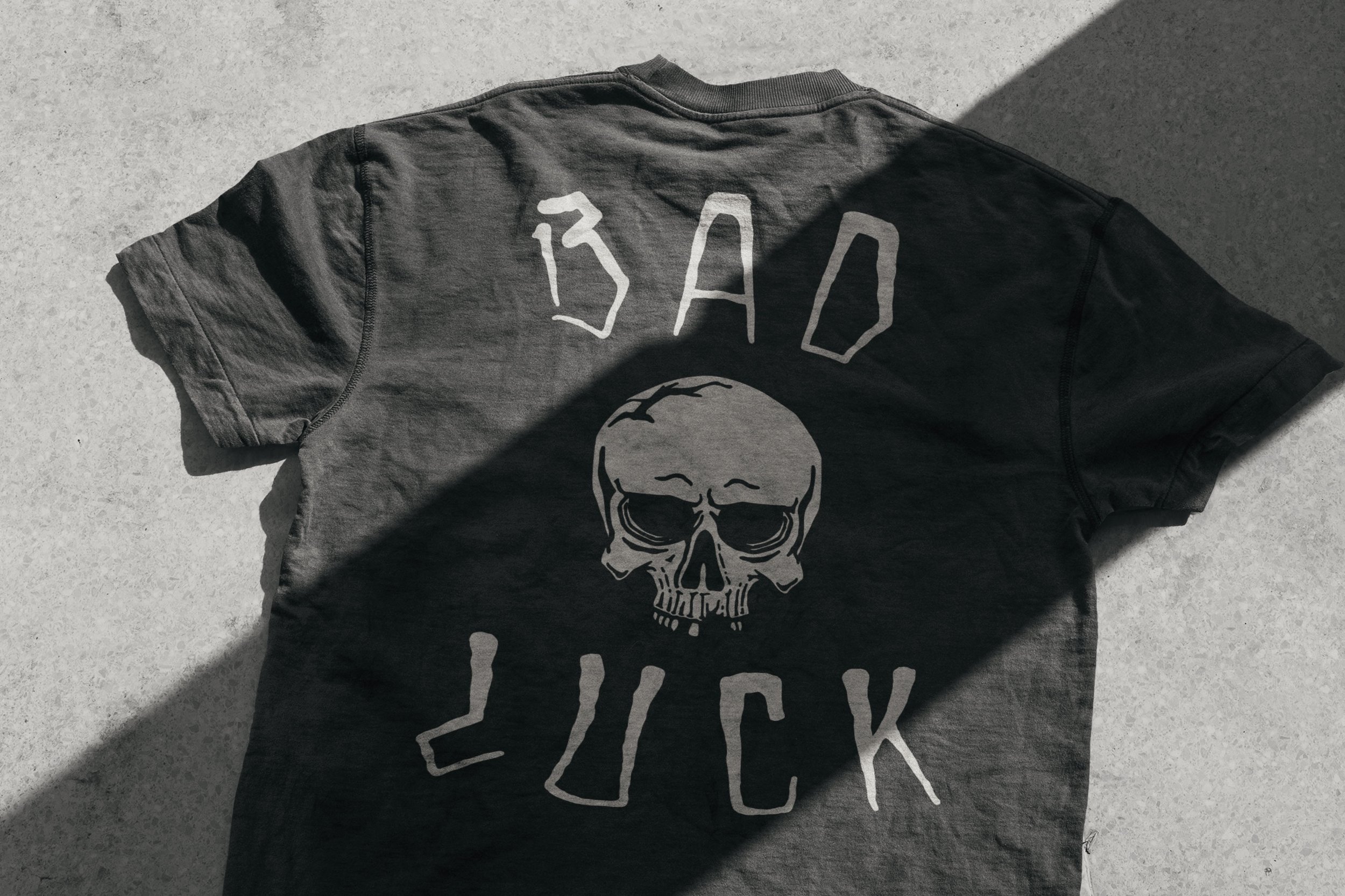 Back of black t-shirt featuring Bad Luck skull brand lockup with distressed lettering