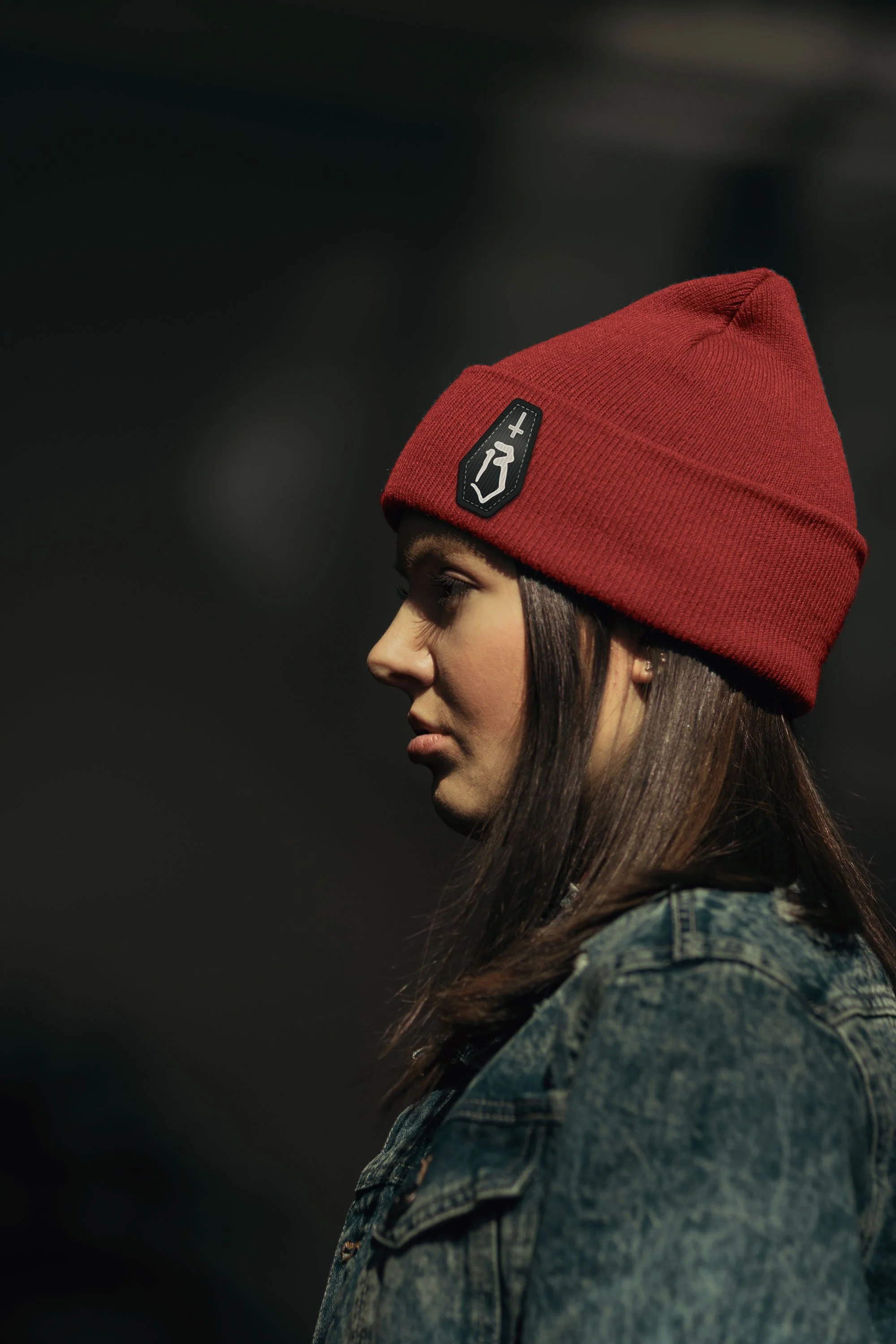 Woman in profile wearing burgundy beanie with Bad Luck coffin logo patch