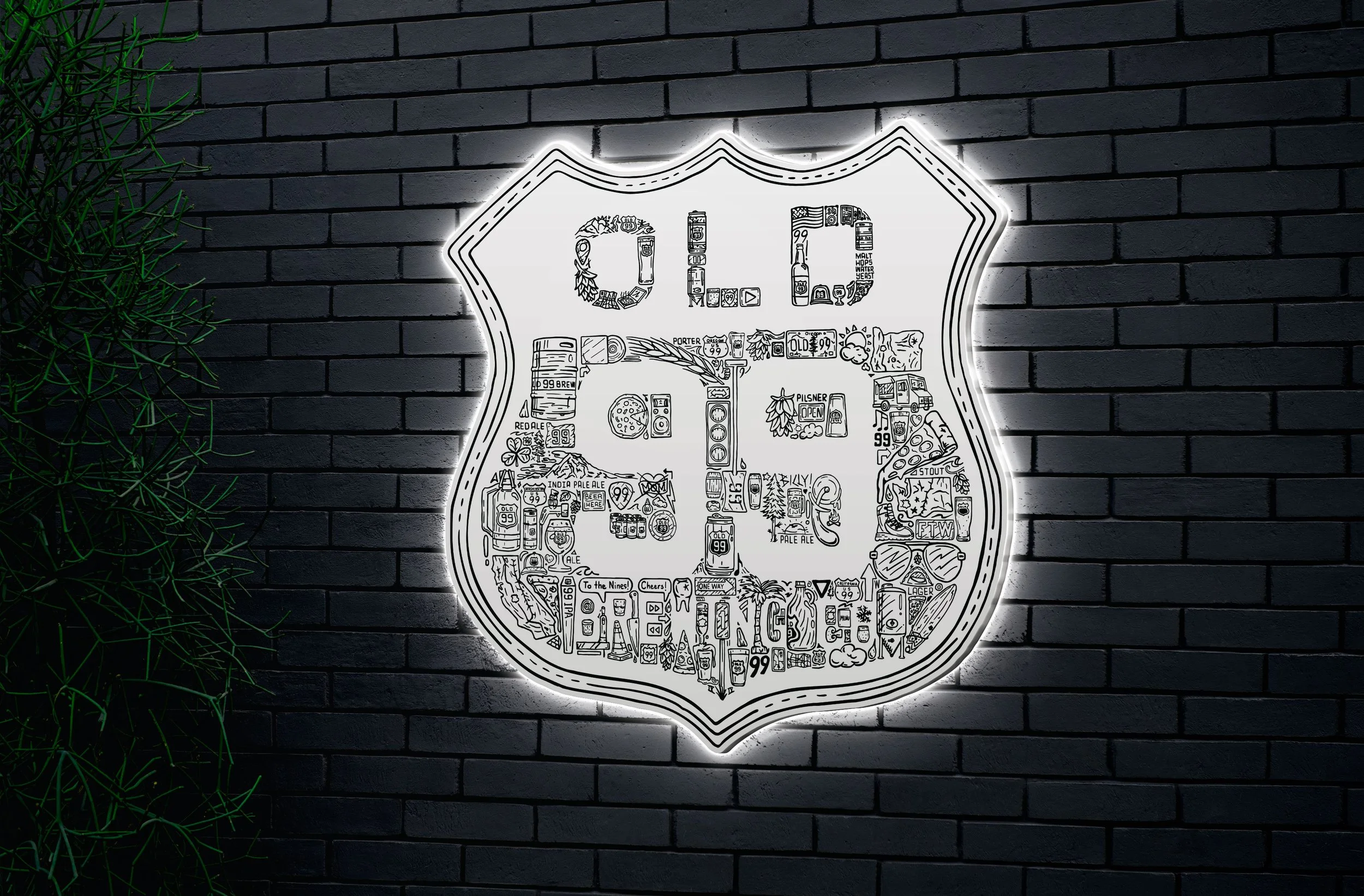Illuminated Iconoflage Old 99 Brewing Co. shield sign on brick wall, creating dramatic nighttime display