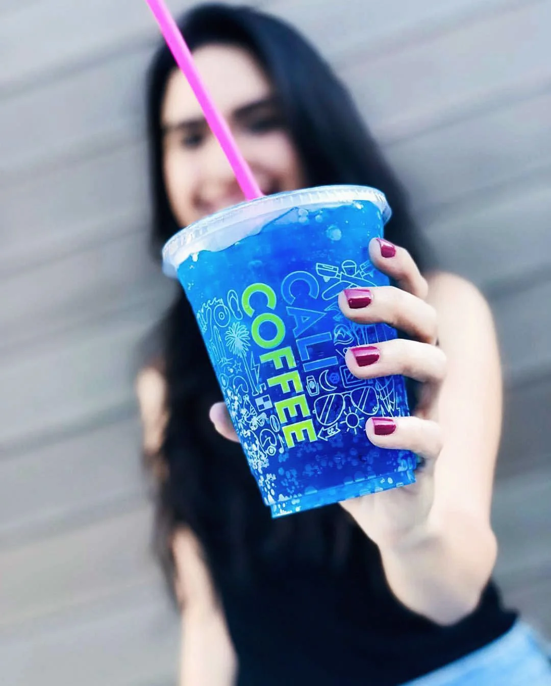 Customer holding Cali Coffee cold cup featuring blue Iconoflage pattern, generating organic social media engagement