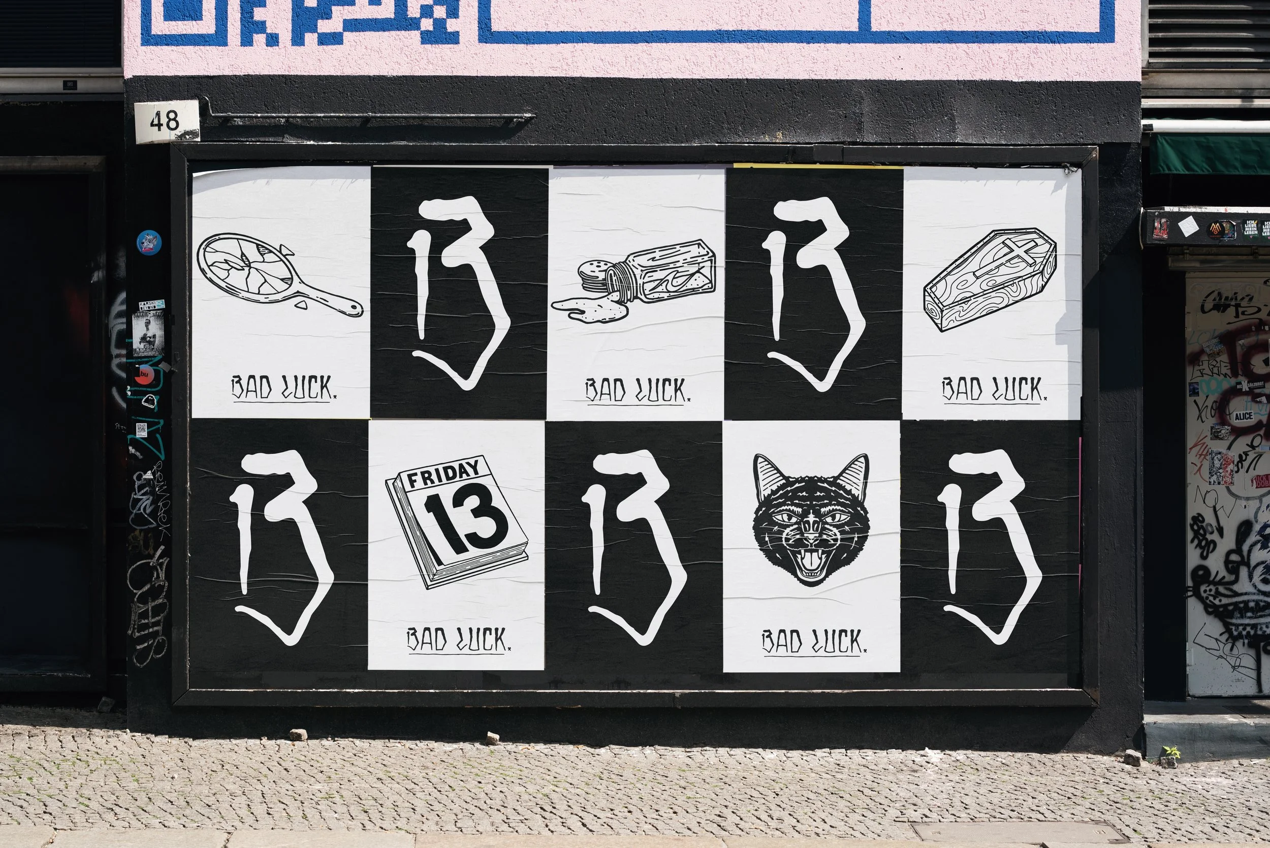 Series of Bad Luck brand posters displayed in urban street setting showing various bad luck symbol illustrations on black and white backgrounds