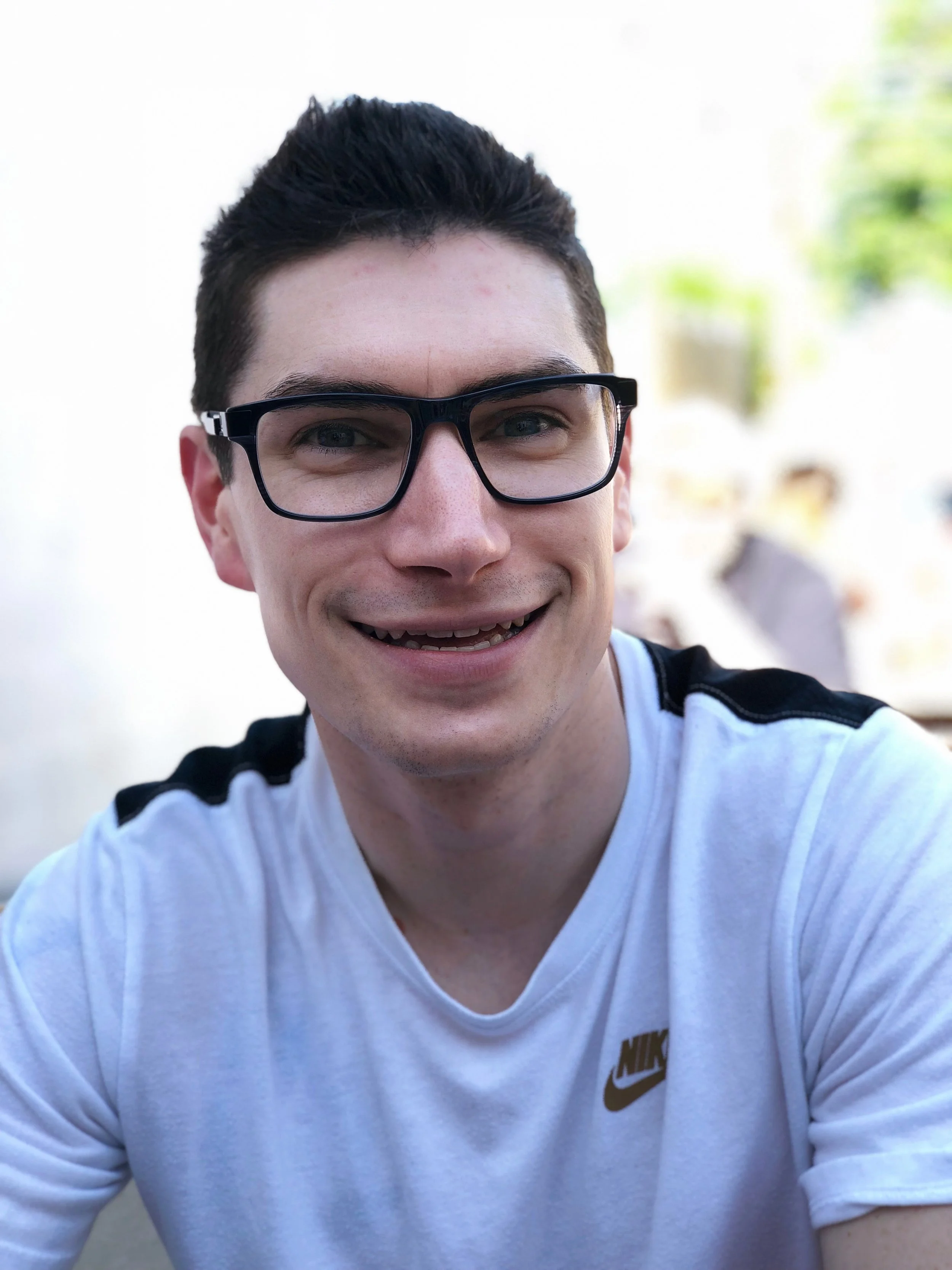 Scott Hofford wearing glasses and a black and white shirt, smiling at camera