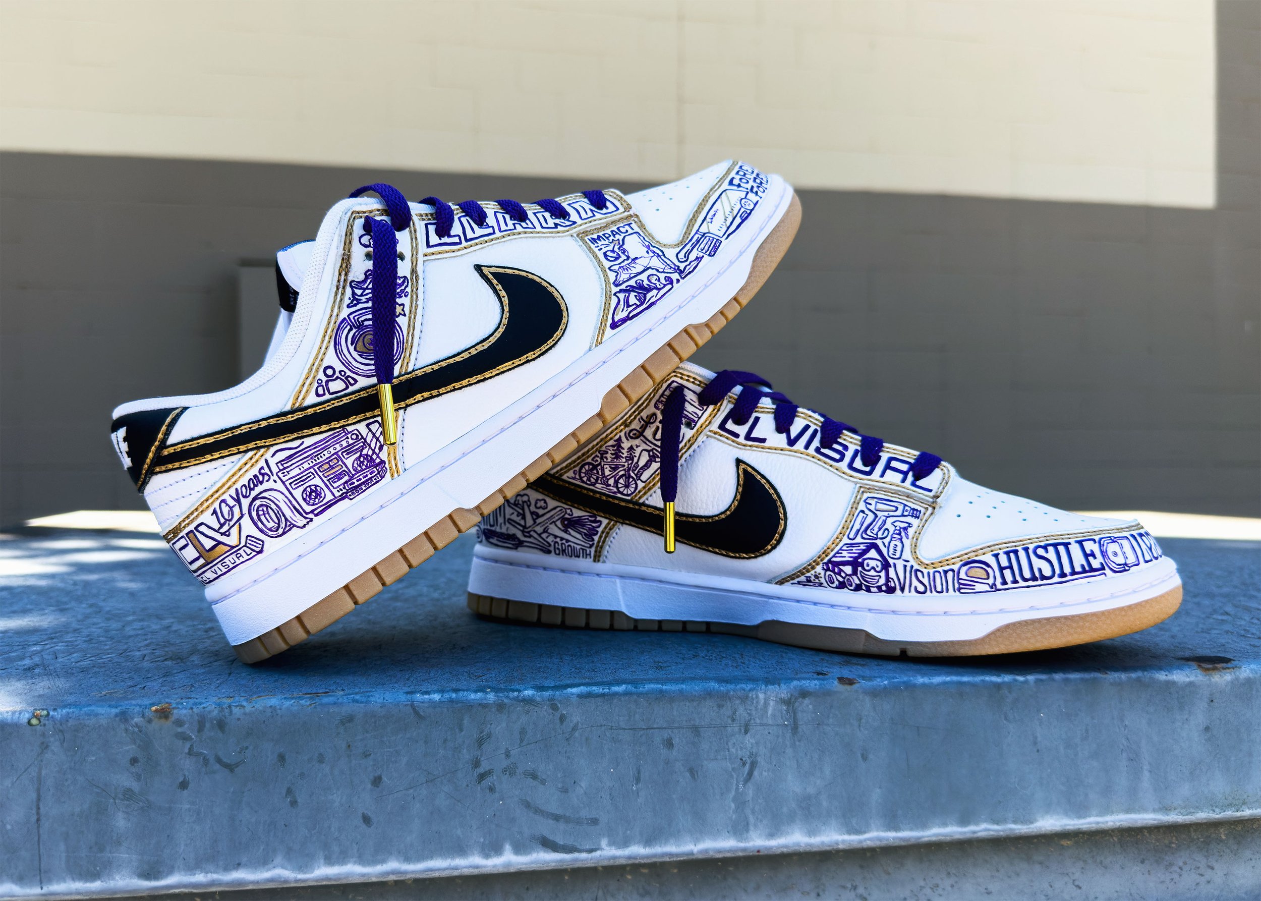 Custom Nike Dunks displayed on metal industrial surface showing CL Visual branding and hand-painted icons