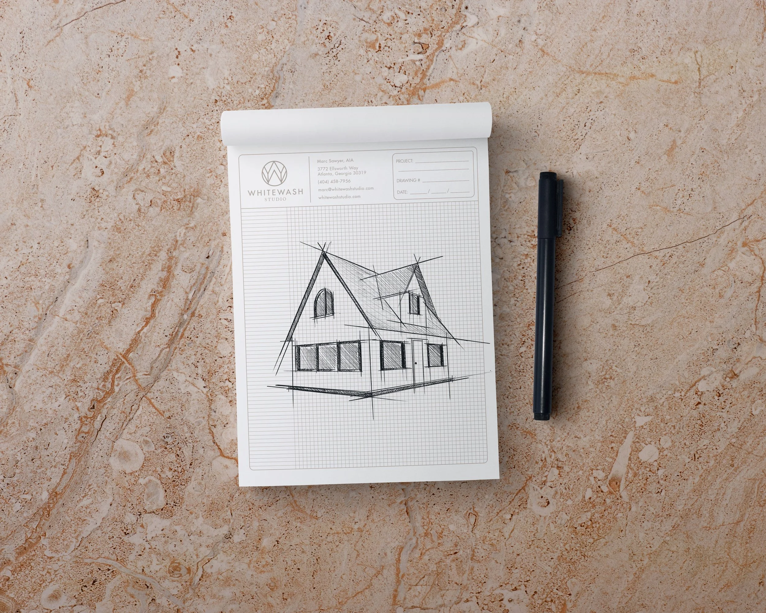 Whitewash Studio branded sketch pad with house illustration and pen on textured surface