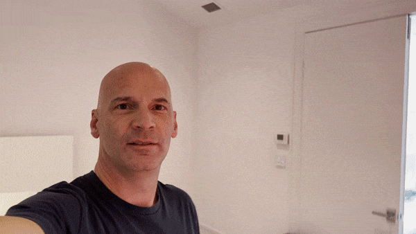 Andrew Tedesco taking a selfie in a white room with minimal decor and turning into a fabulous graffiti mural room for kids.