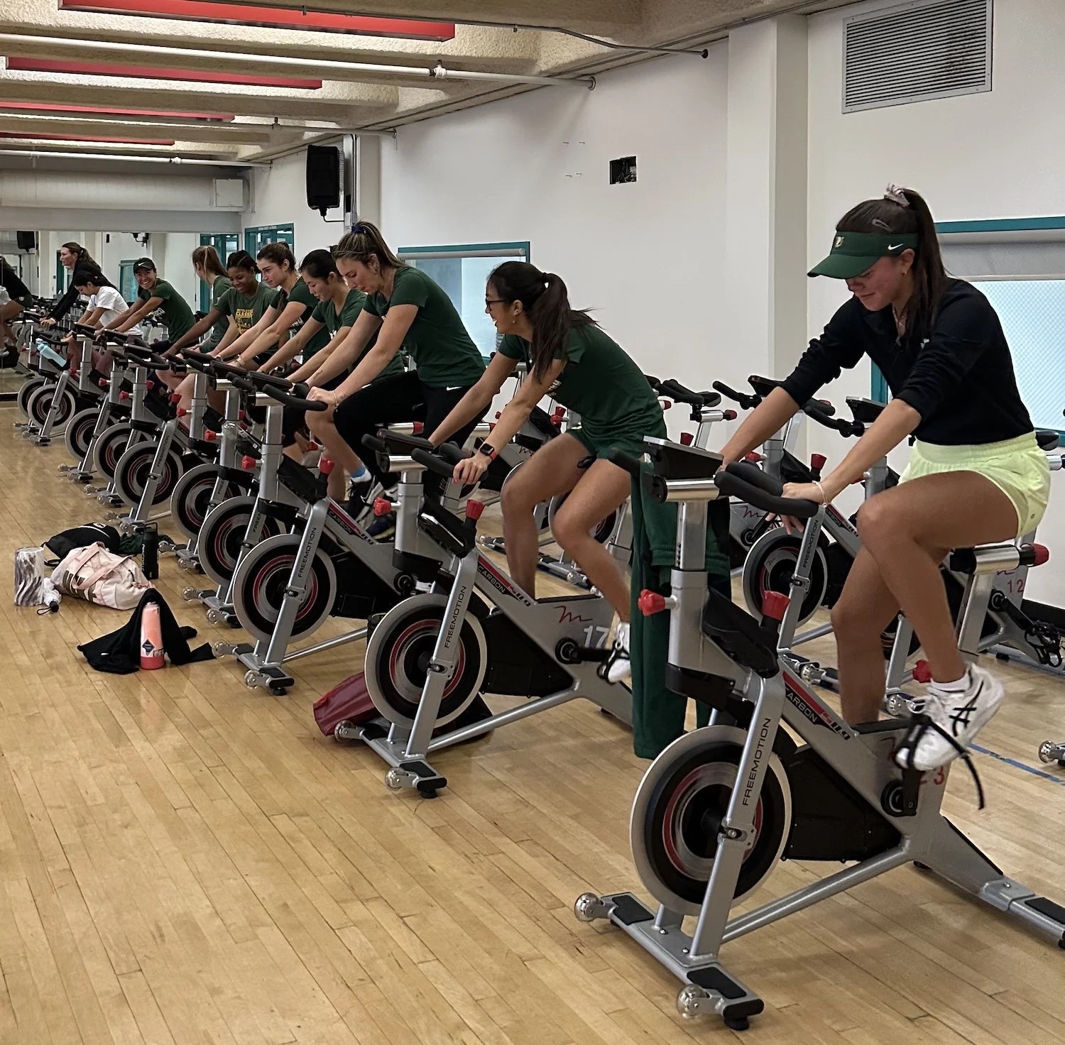 USF women's tennis team during a training session, riding stationary bikes.