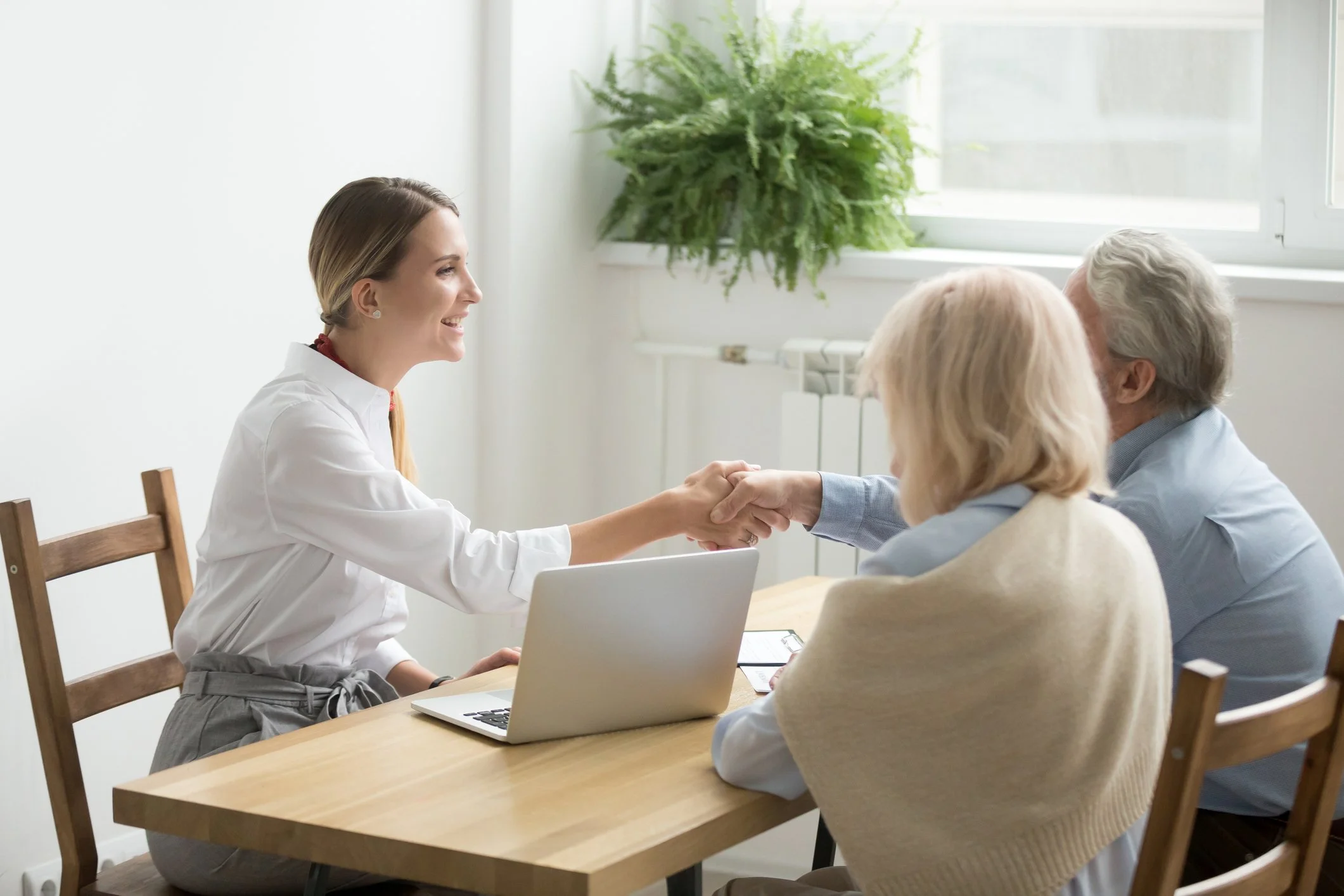 A daily money manager reviewing financial information with an older couple in their home.