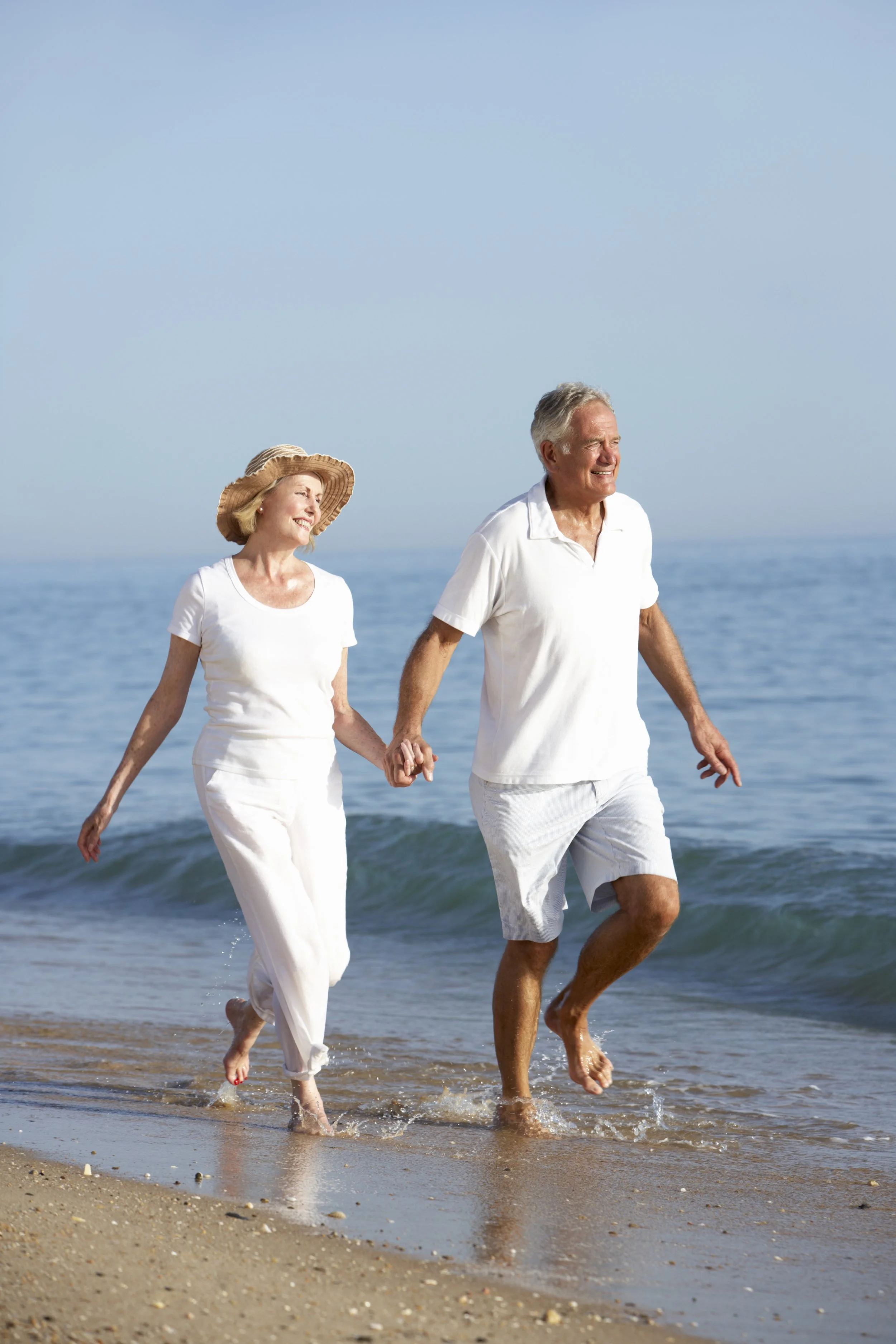 An older couple smiling on the beach, representing the benefits of daily money management for seniors