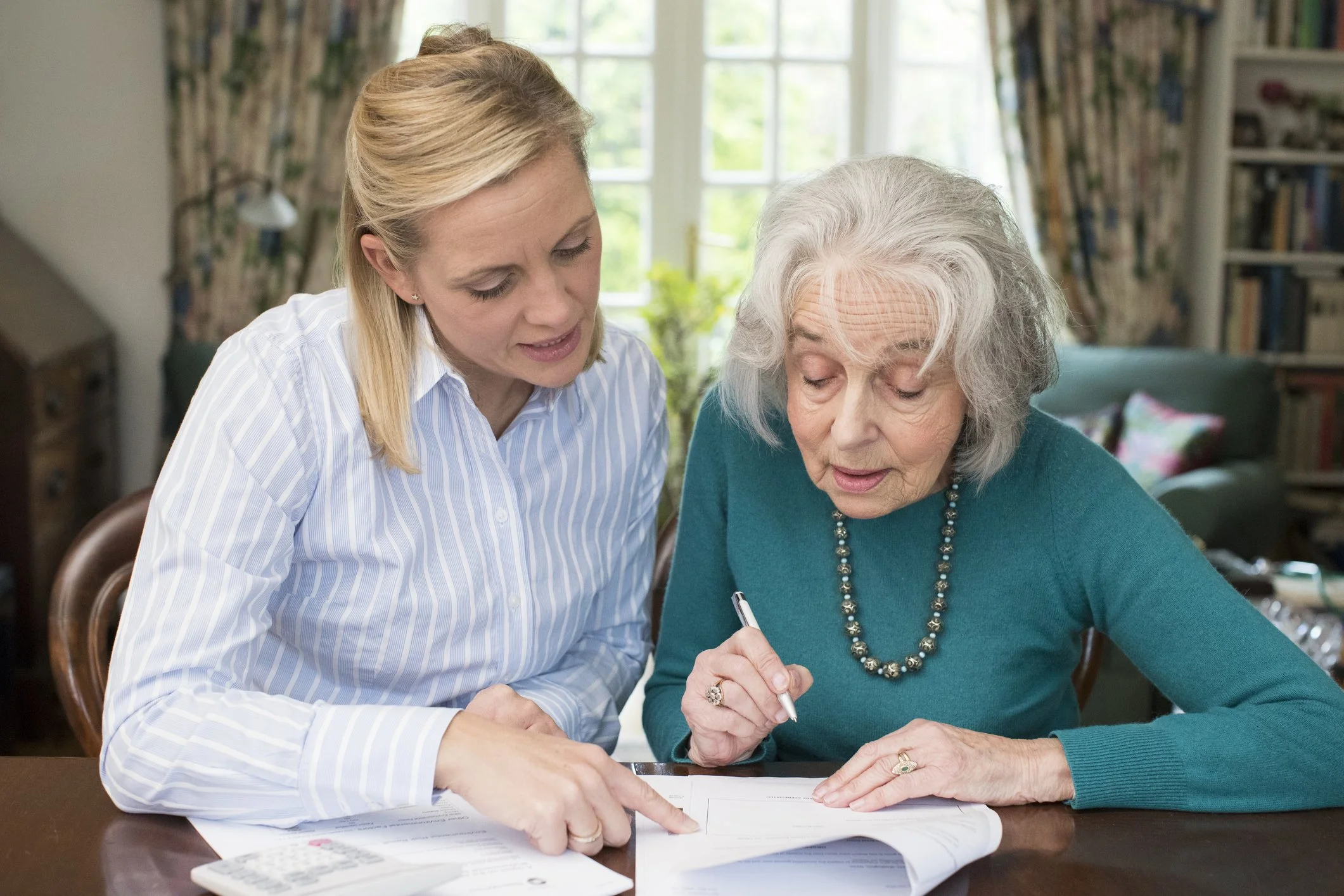 Daily Money Manager helping senior woman with paperwork and bill pay in her home