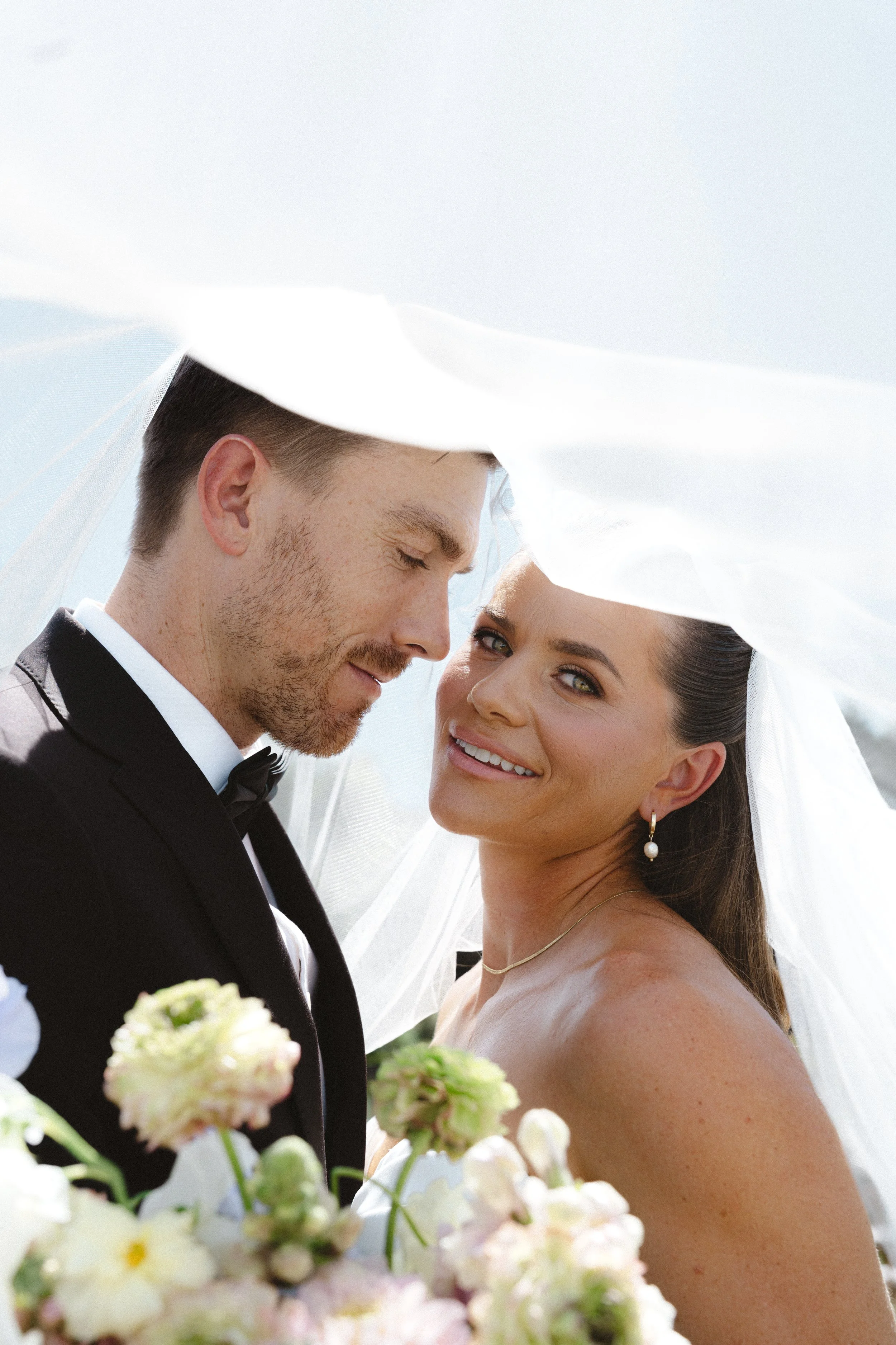 Bride and groom under veil at Monserate Winery wedding in Fallbrook California with soft natural light and romantic florals