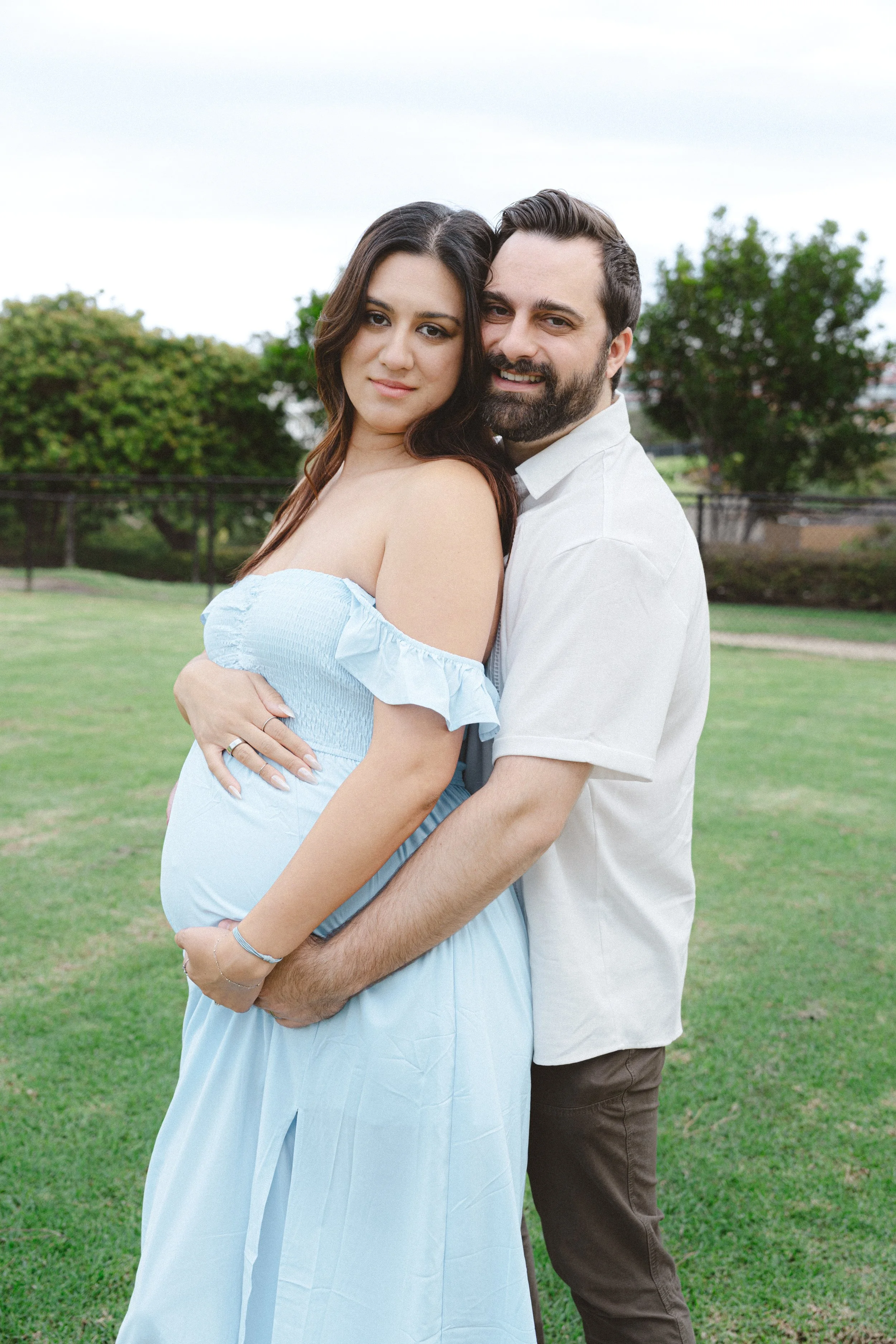 Expecting couple embracing in Dana Point, California during an outdoor maternity photography session by the Salt and Serenity.