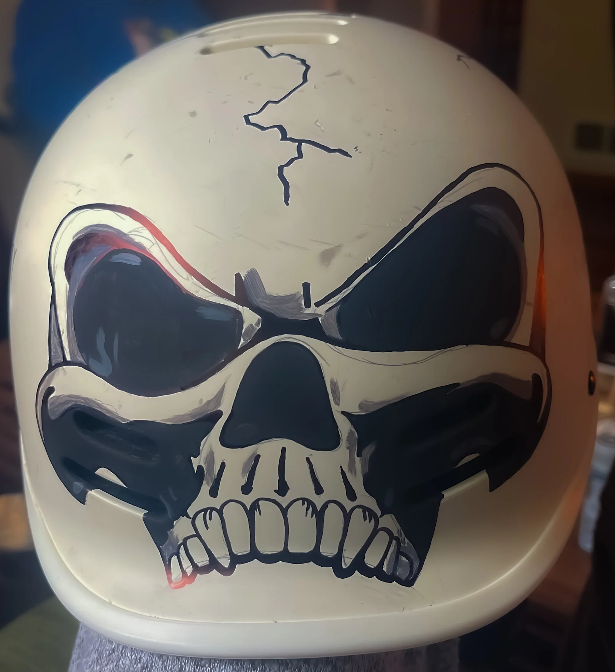 A white helmet with a black and gray skull design painted on the front.