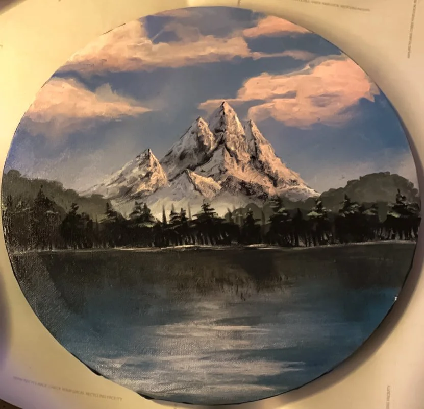 Painting of a snow-capped mountain range, possibly the Grand Tetons, with a body of water and trees in the foreground, under a cloudy sky.