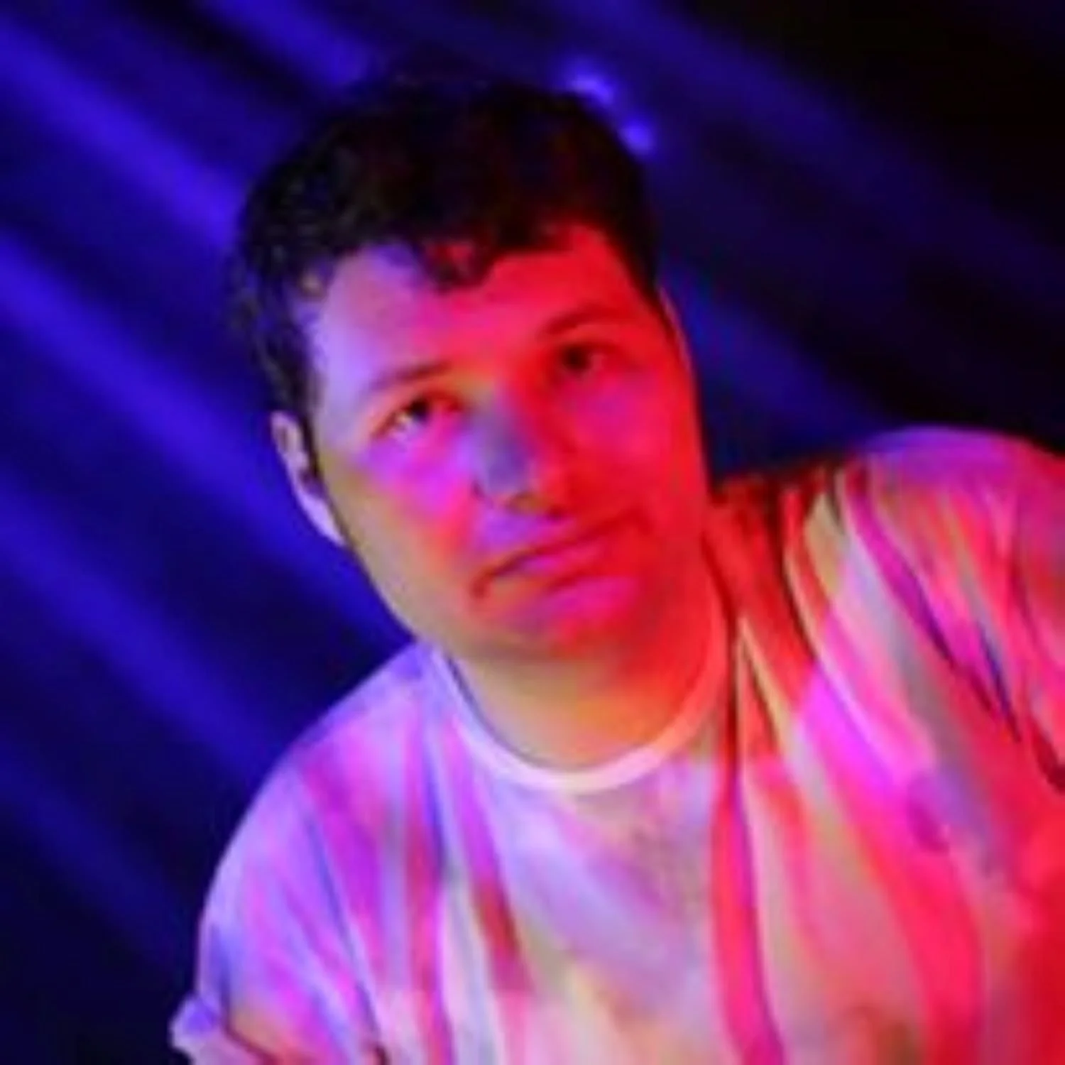 Kyle head and shoulders view, with multicoloured lights shining on him