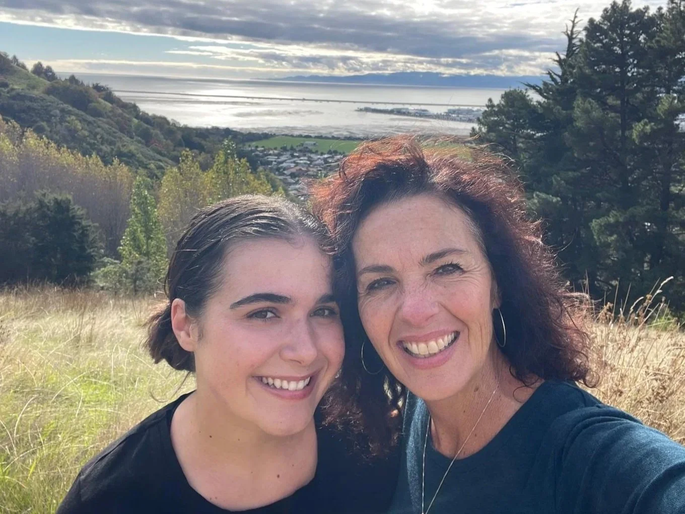 Mich and her daughter with a valley and shoreline background