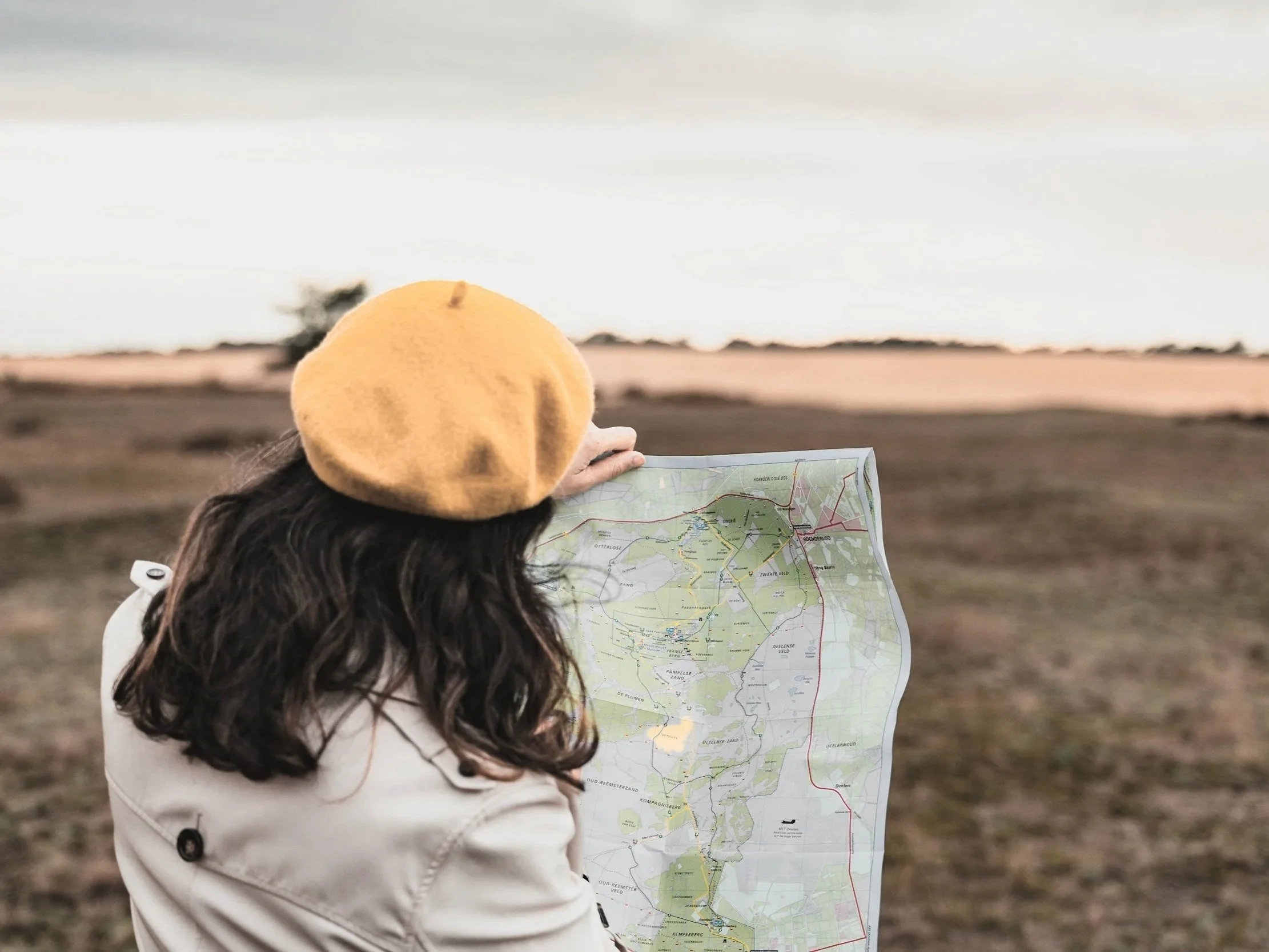 A woman standing in an open field holding a map.