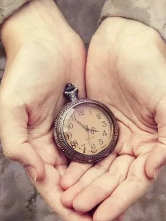 Hands gently holding a small  old clock.