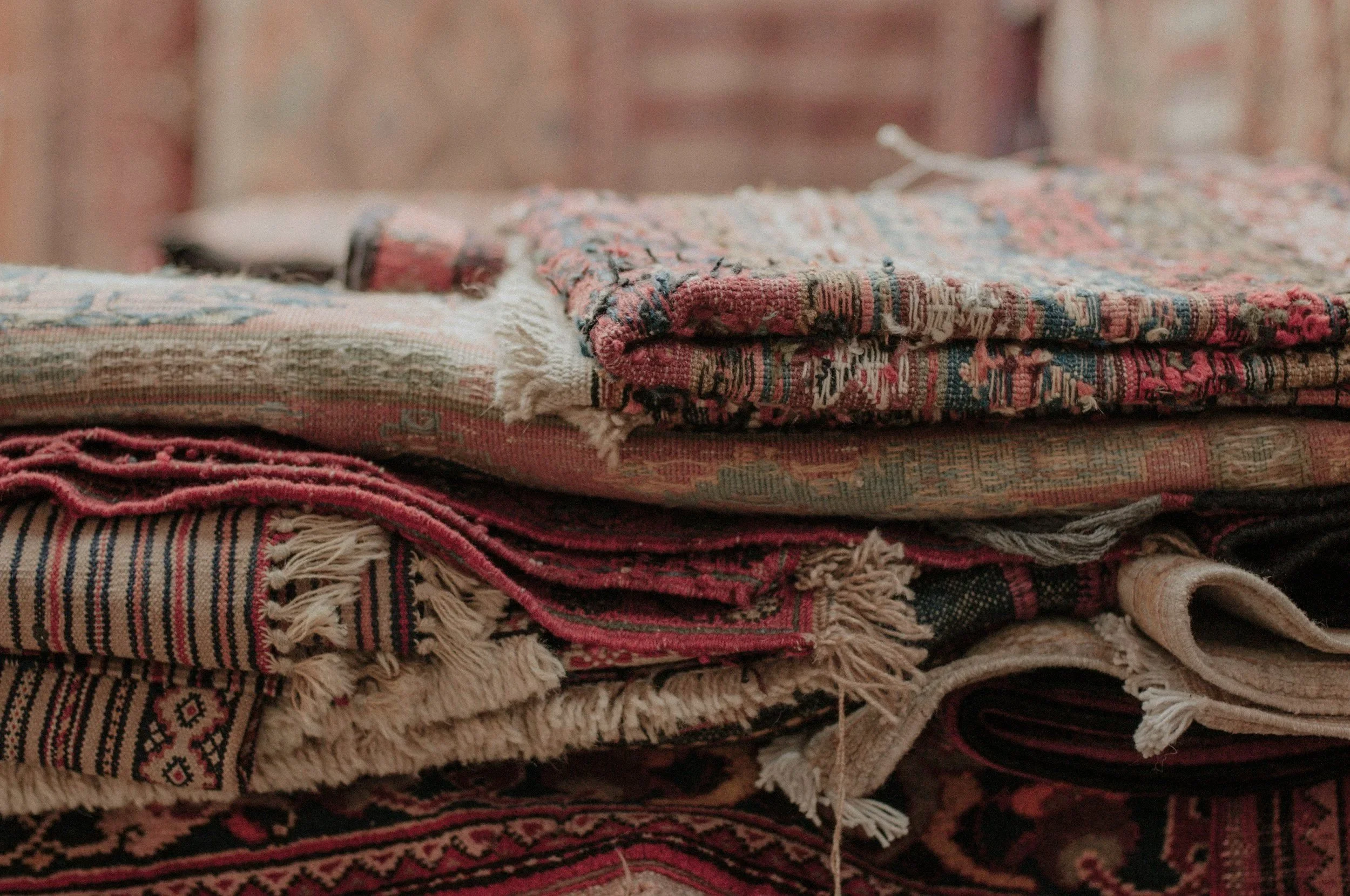 A stack of folded woven rugs and tapestries.
