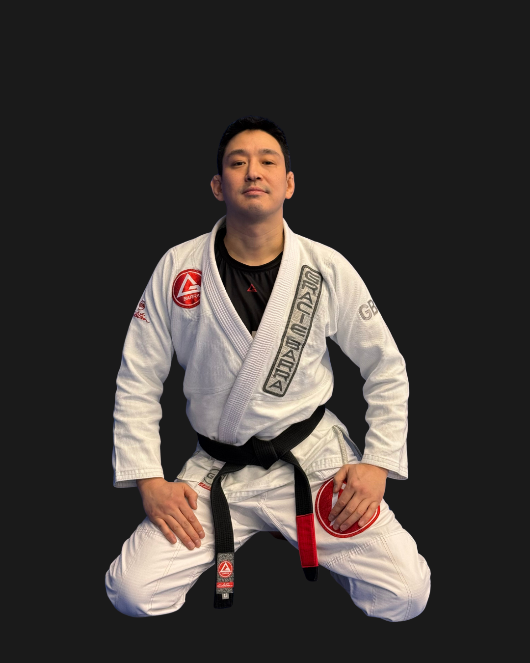 A person in a white Brazilian Jiu-Jitsu gi with patches, kneeling with hands on thighs, against a black background.