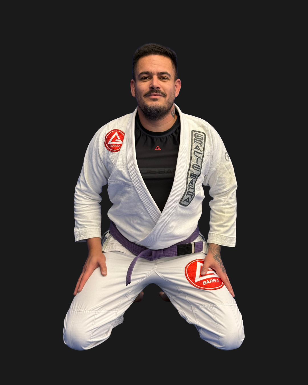 A man in a white Brazilian Jiu-Jitsu gi with patches, kneeling in a ready stance against a black background. Text on top left reads 'Coach Alex' and 'GB K'.