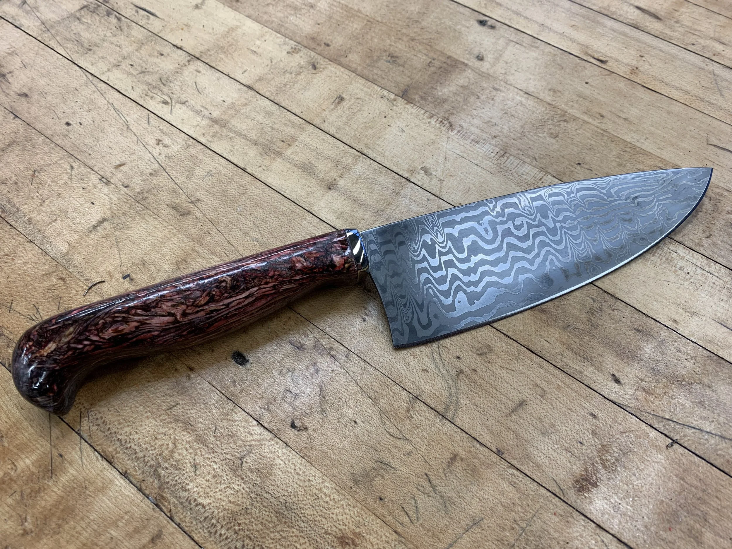 Chef's knife, made as a gift. (2023)
Blade: Laminated 1095 and 15N20, with pure nickel sheet for contrast.
Handle: Compressed resin bonded wood shaving, dyed red, with a nickel silver bolster.